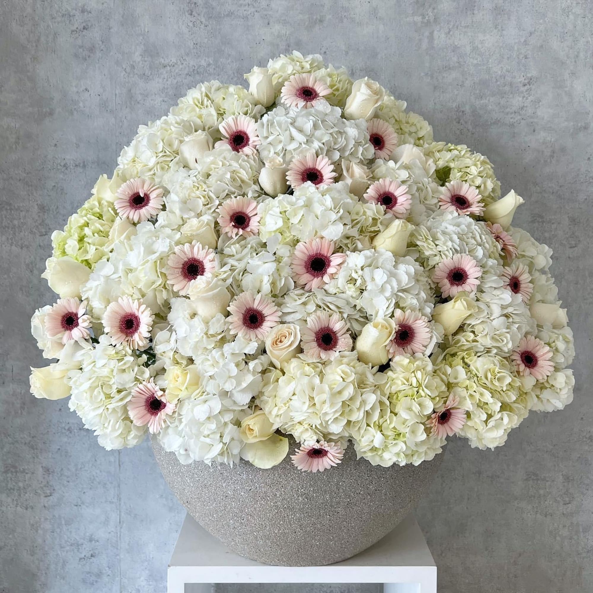 Large white floral arrangement with pale pink daisies in a glittery vase