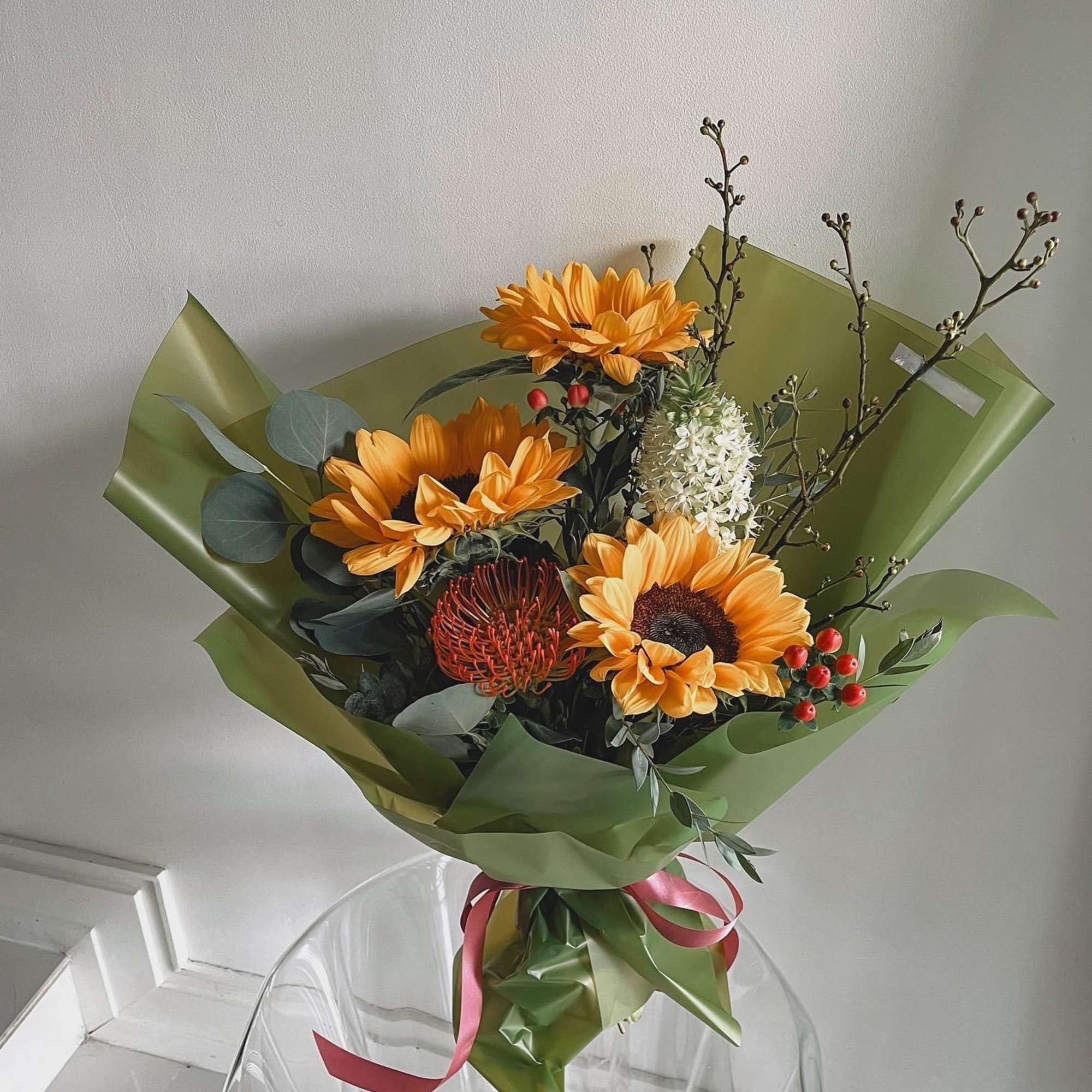 Bouquet of orange sunflowers wrapped in green paper
