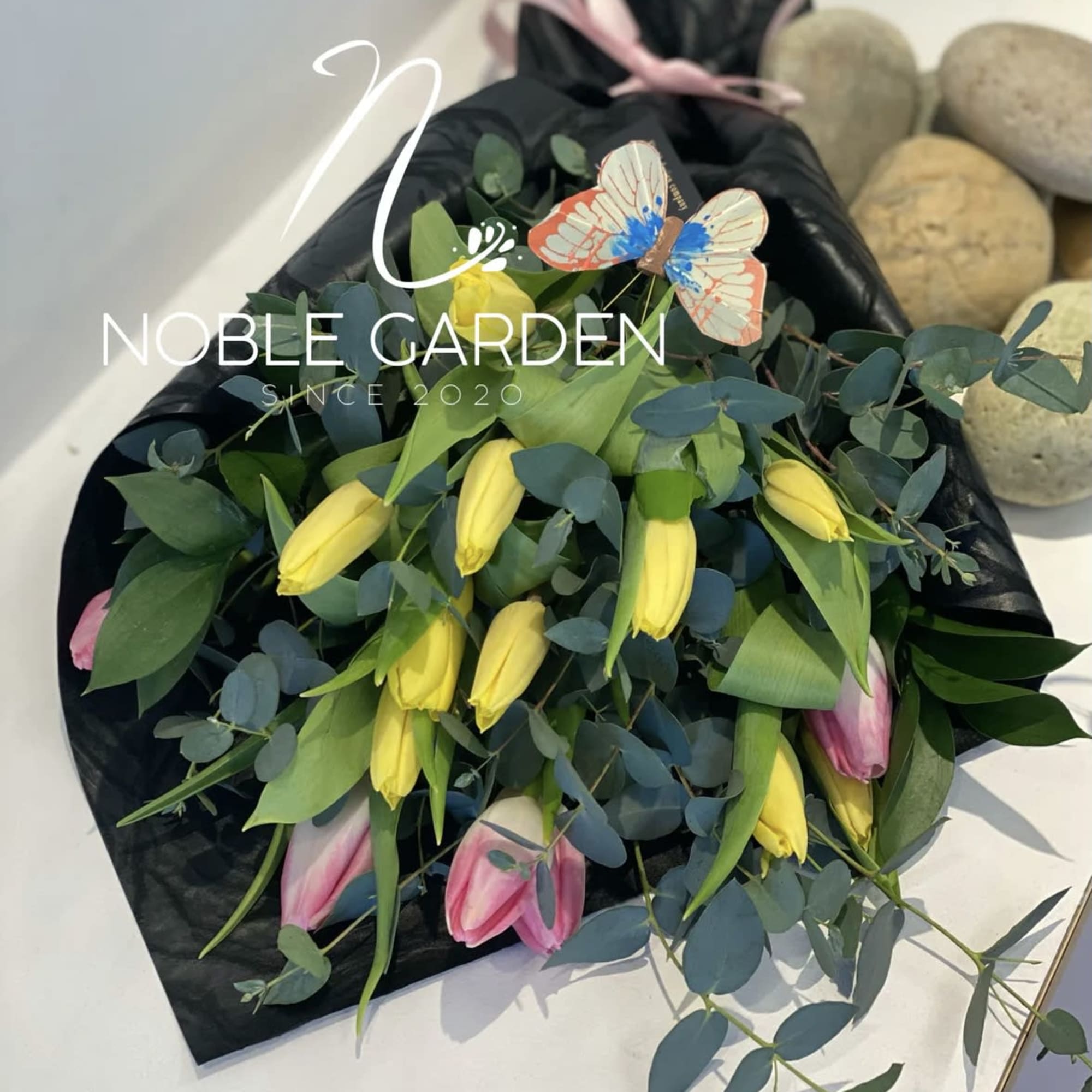 Bouquet of yellow and pink tulips with eucalyptus in black wrap