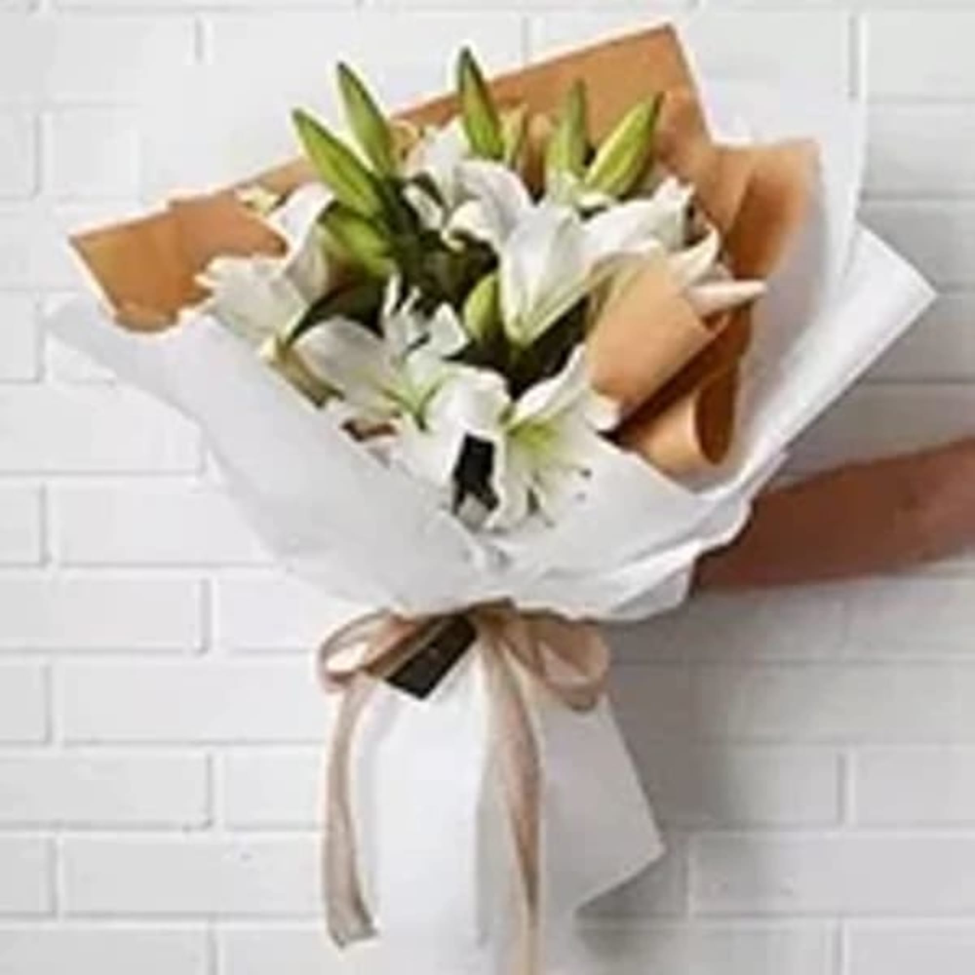 Bouquet of white lilies wrapped in brown and white paper
