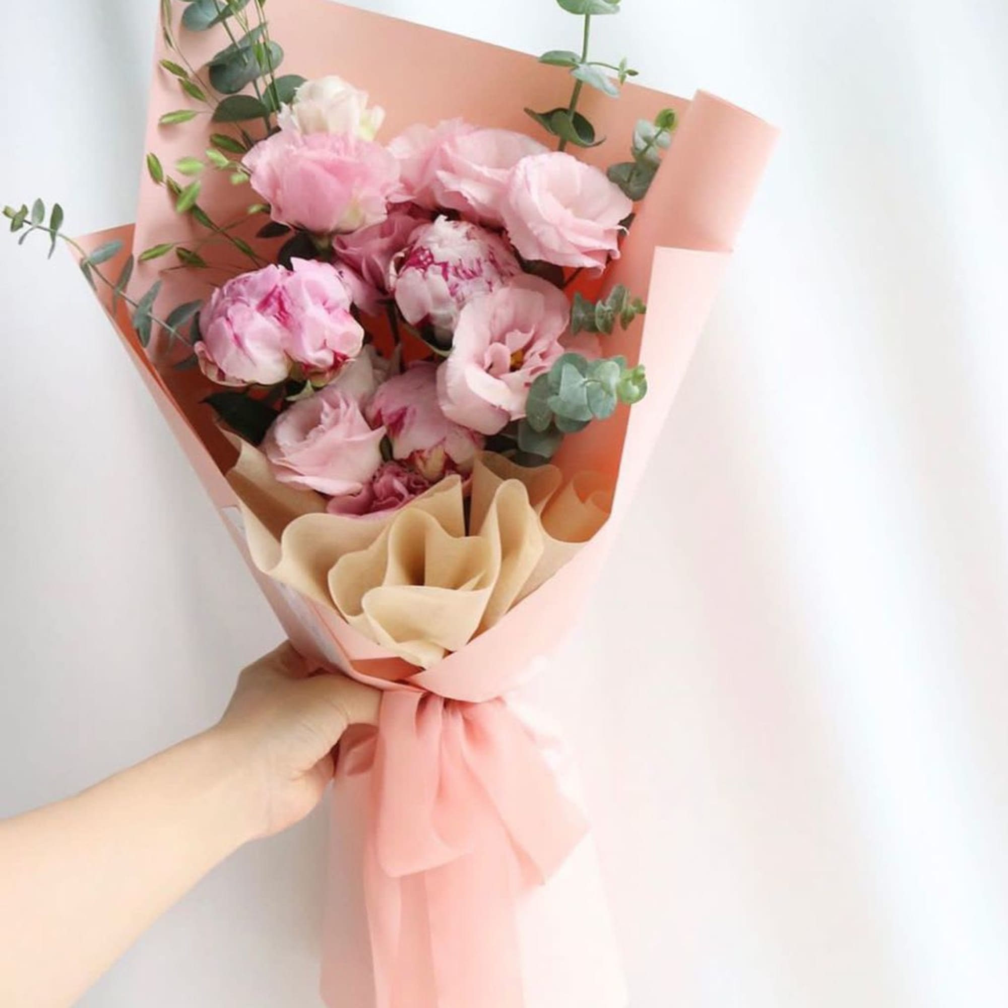 Pink bouquet with peonies and eucalyptus wrapped in peach paper