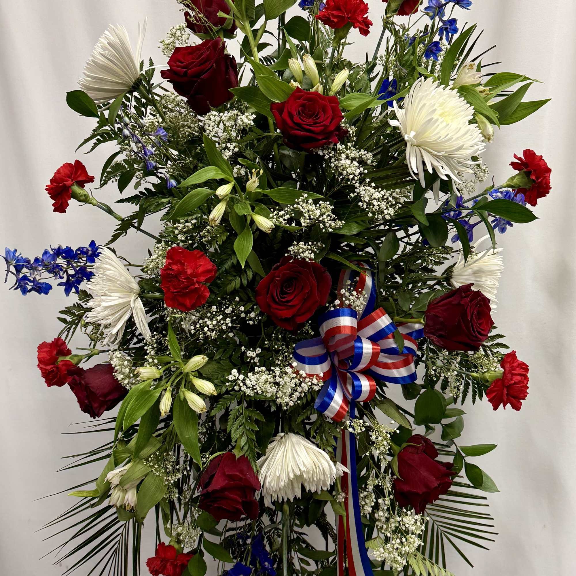 Large standing floral spray with red roses, white chrysanthemums, and blue flowers