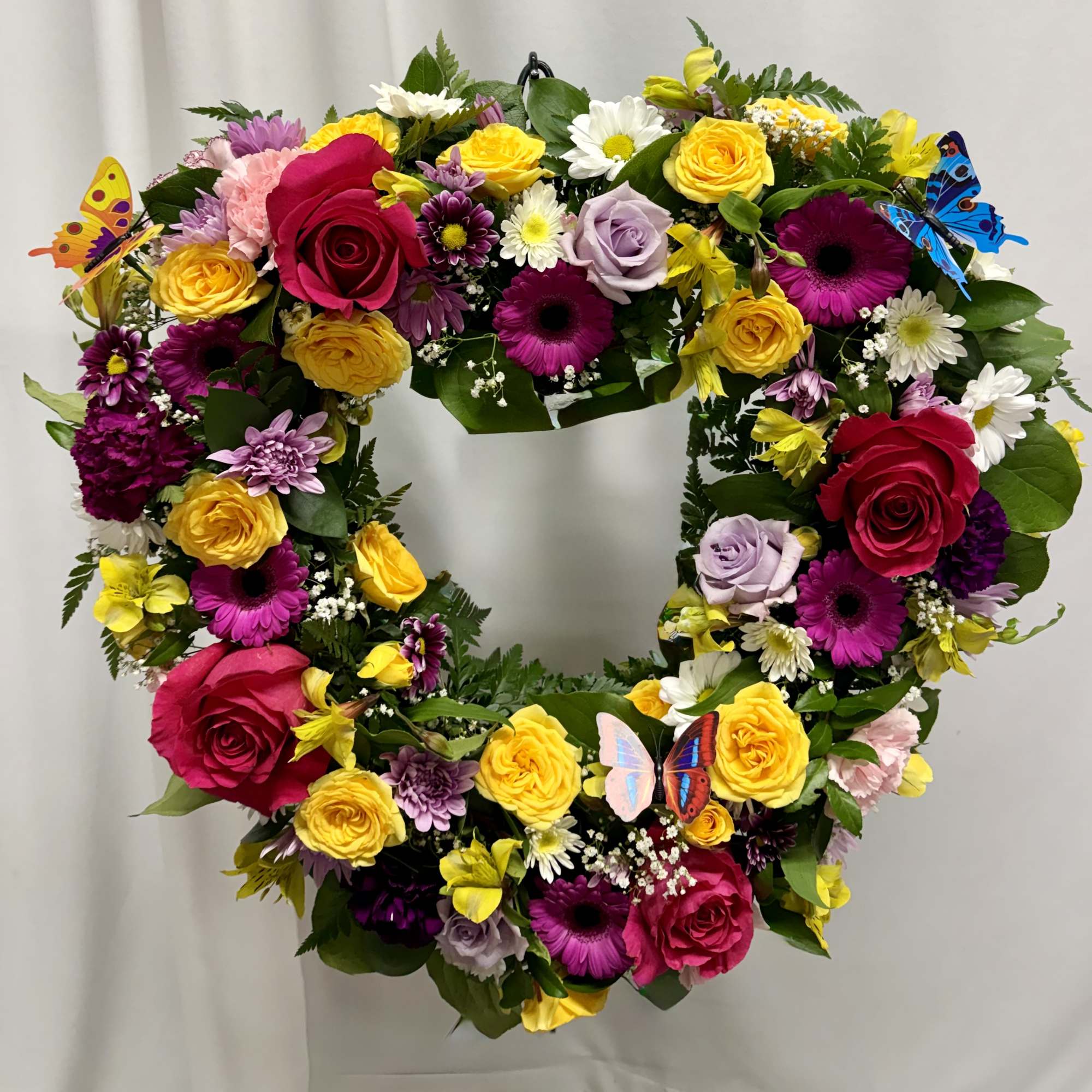 Heart-shaped floral wreath with roses, daisies, and butterflies