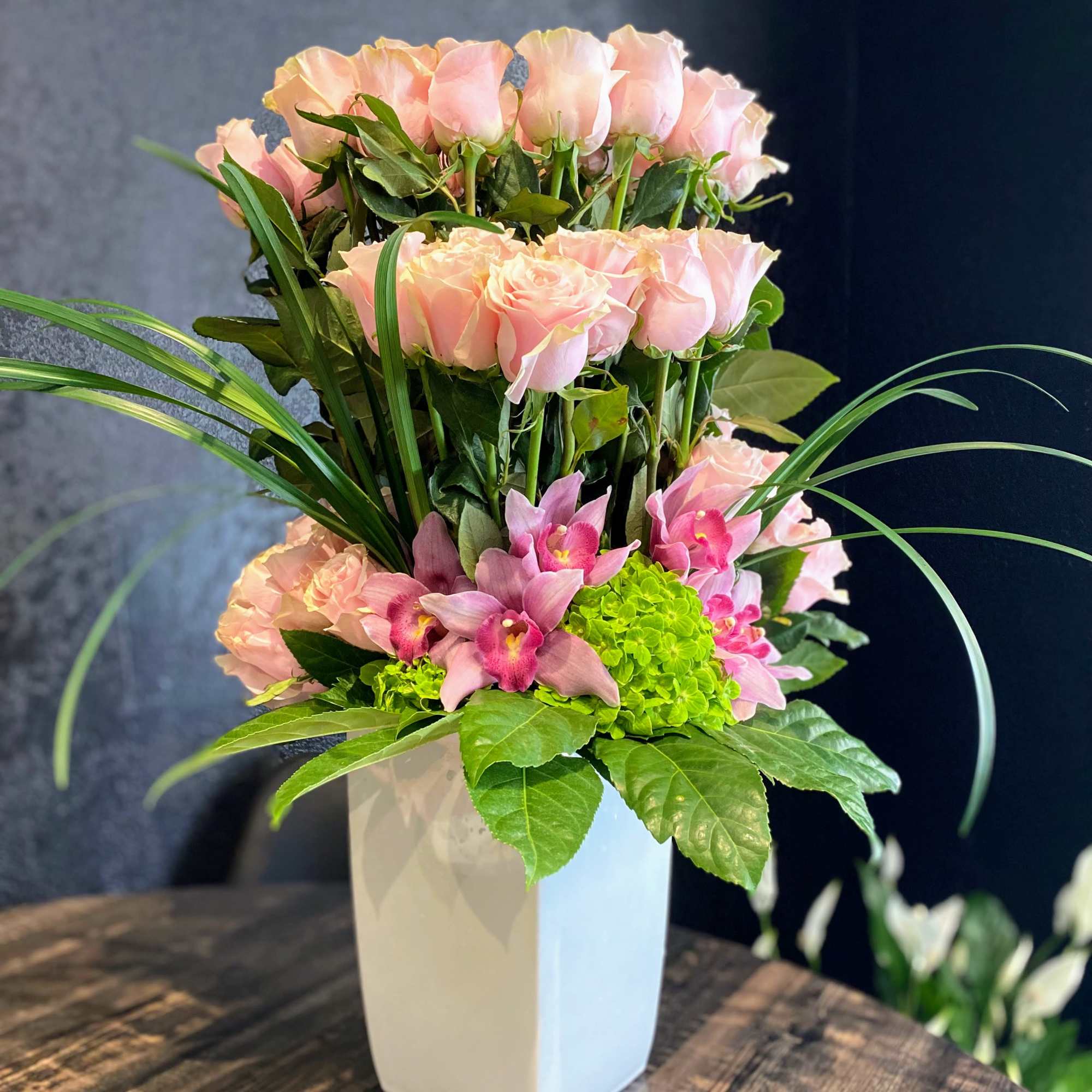 Pink roses and orchids arranged in a white vase