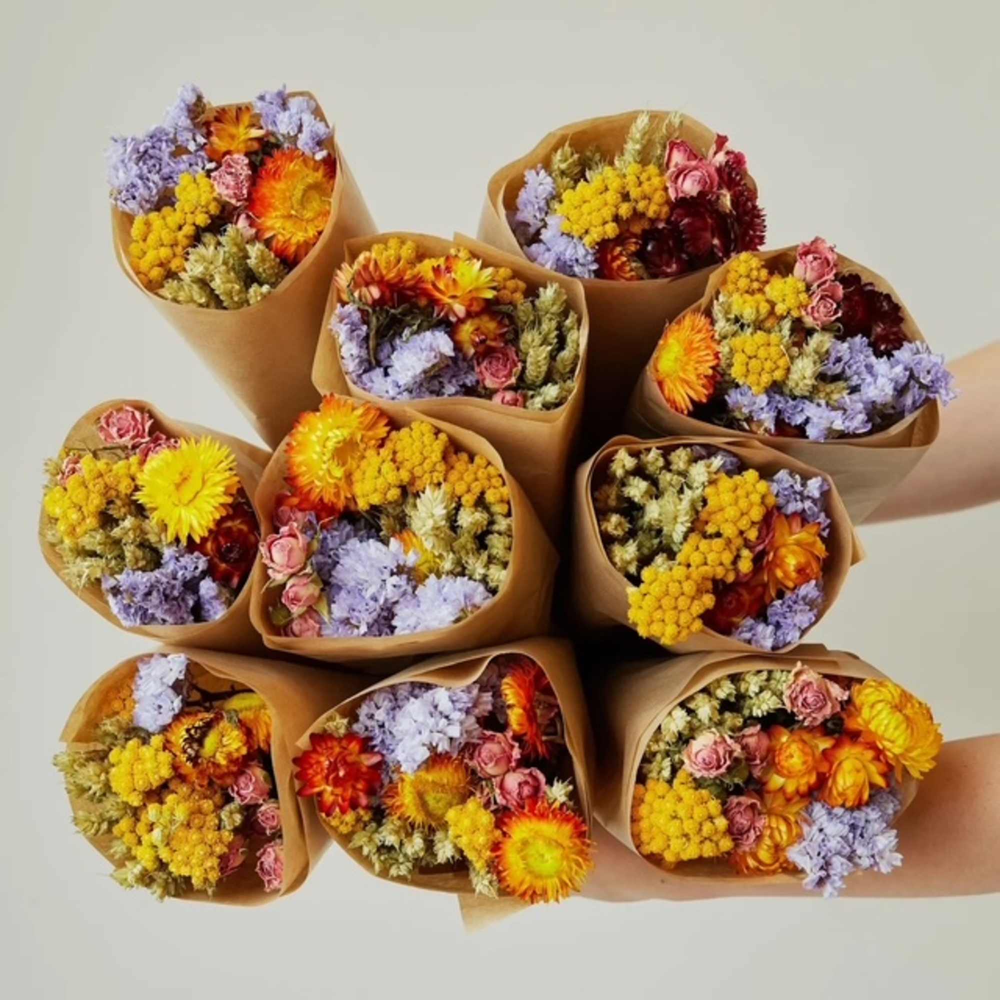 Several small bouquets of colorful flowers wrapped in brown paper