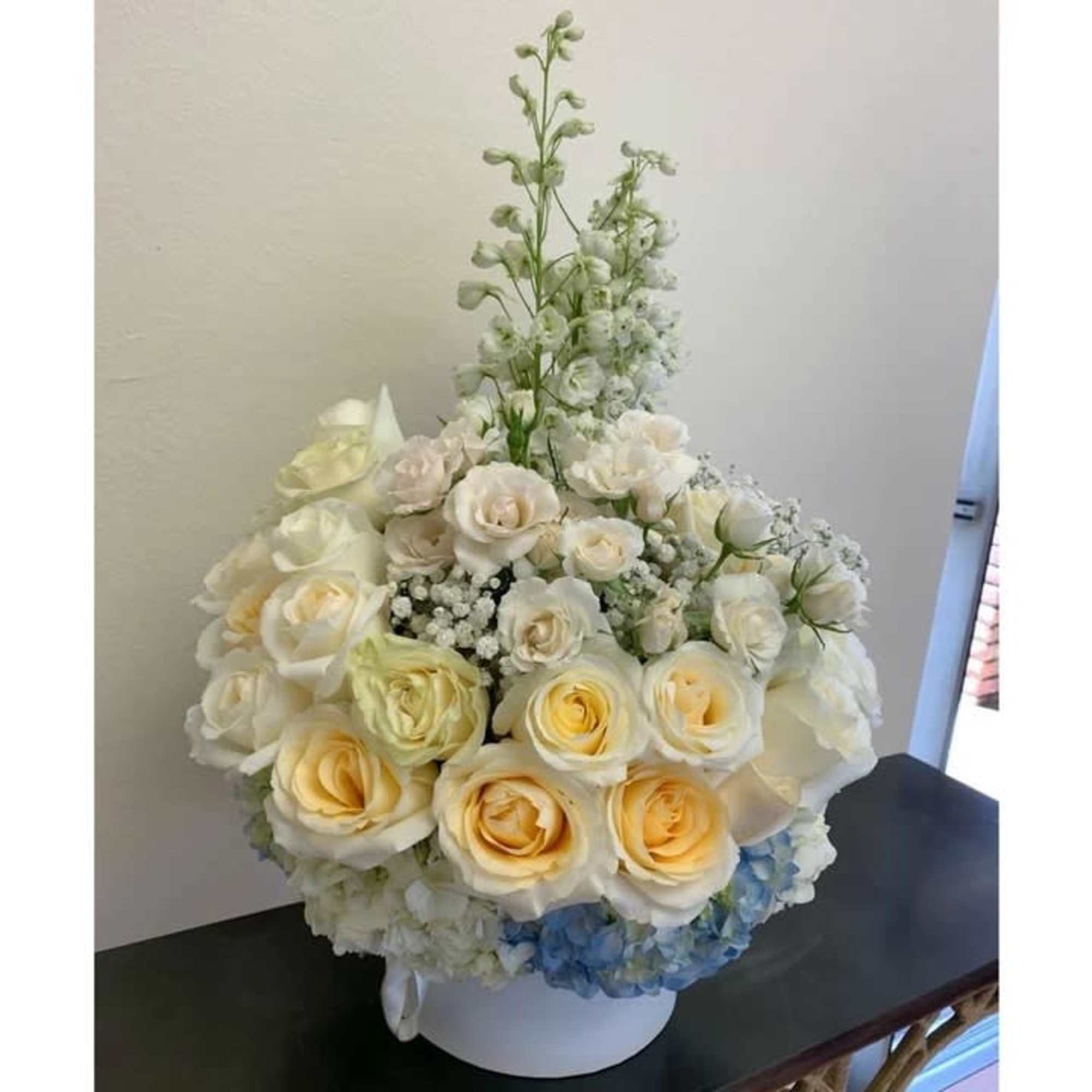 White and pale yellow roses arranged in a round white vase