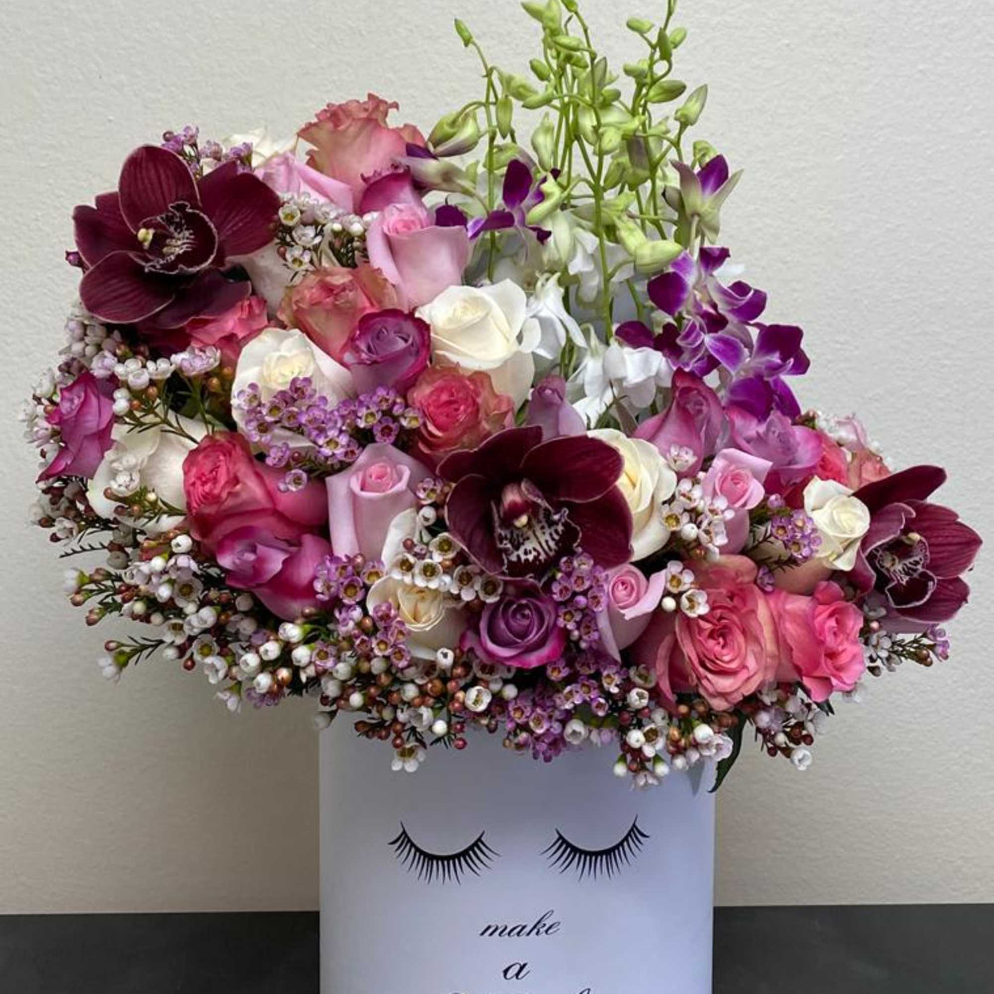 Pink and purple bouquet in a white box with eyelash graphic and "make a Wish" text