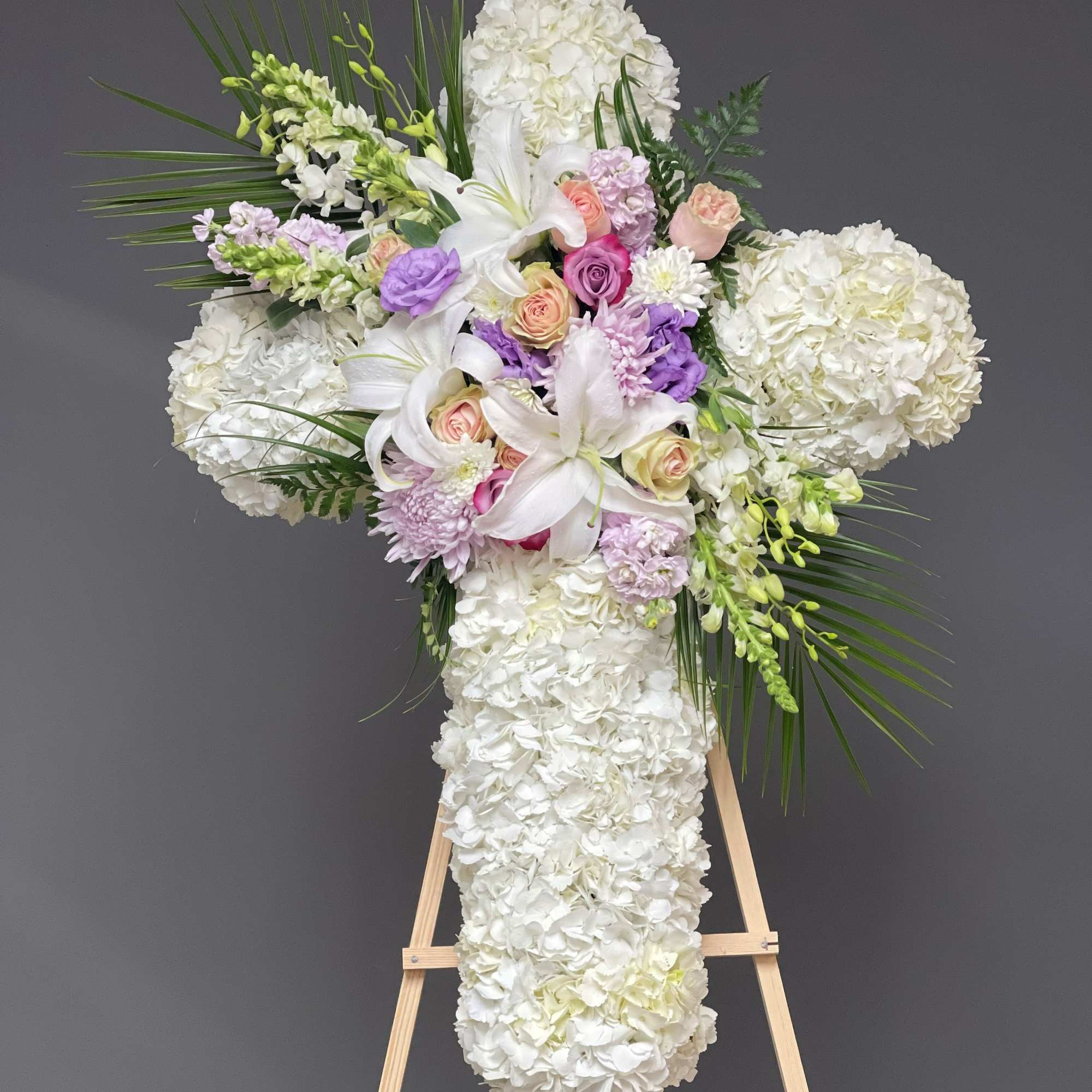 White floral cross arrangement with lilies, roses, and hydrangeas on an easel, photo 2 of 2