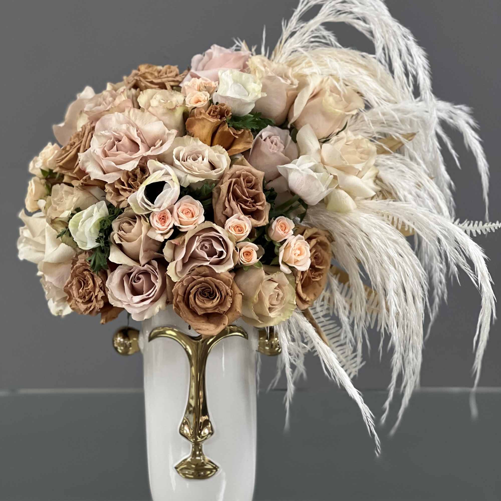 Bouquet of blush and beige roses in a white vase with white feathers
