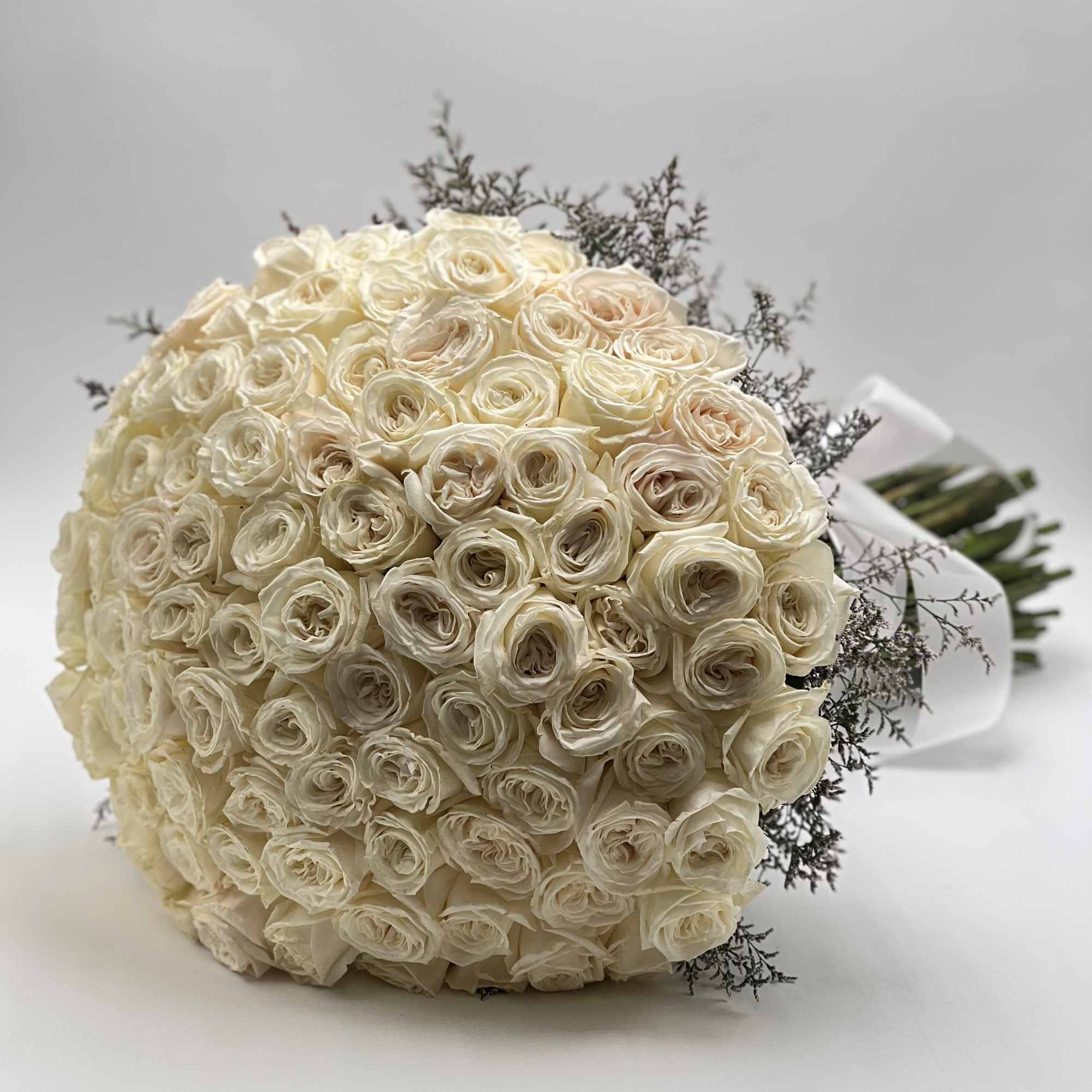 Large bouquet of cream roses with dark filler sprigs