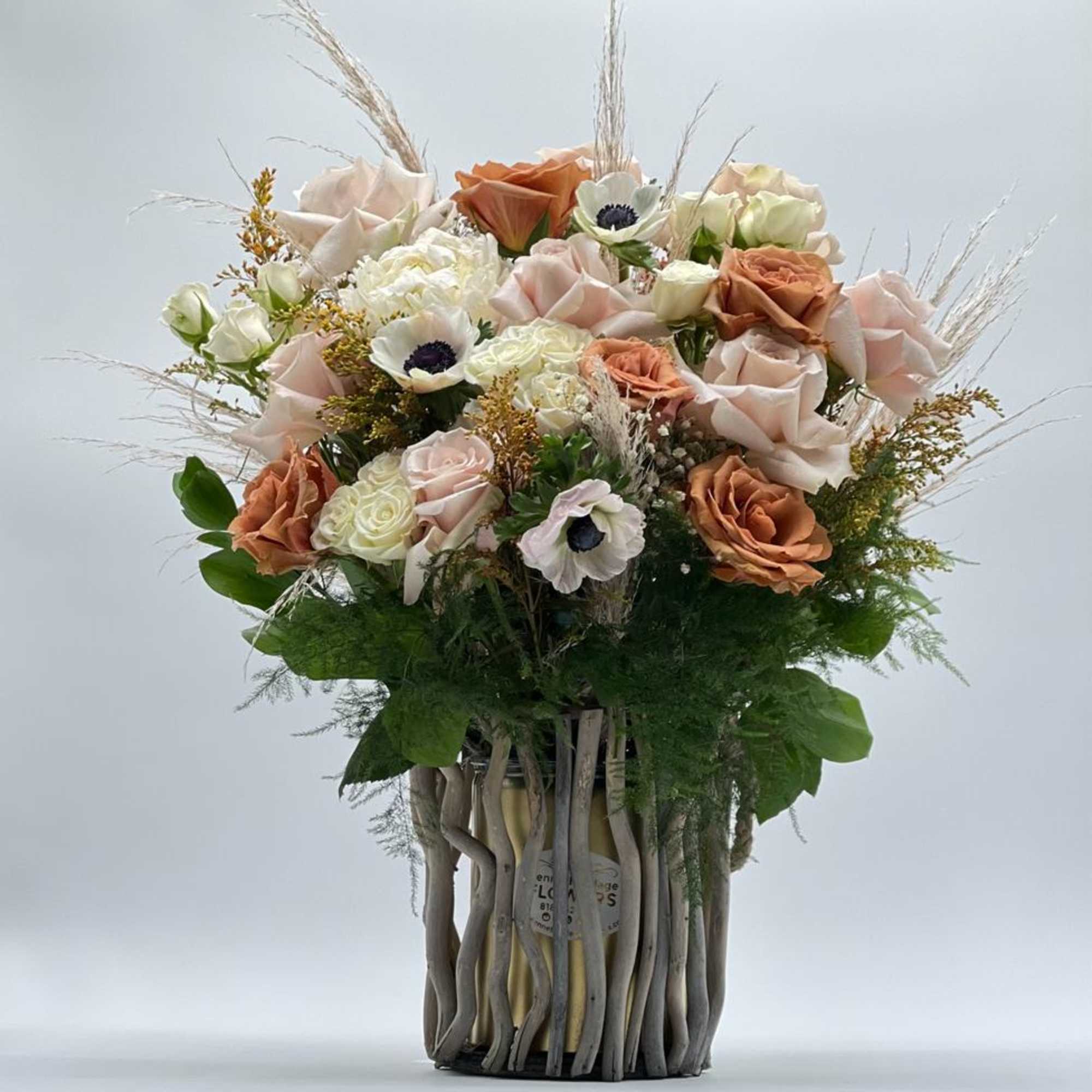 Bouquet of peach and blush roses in a tall decorative vase