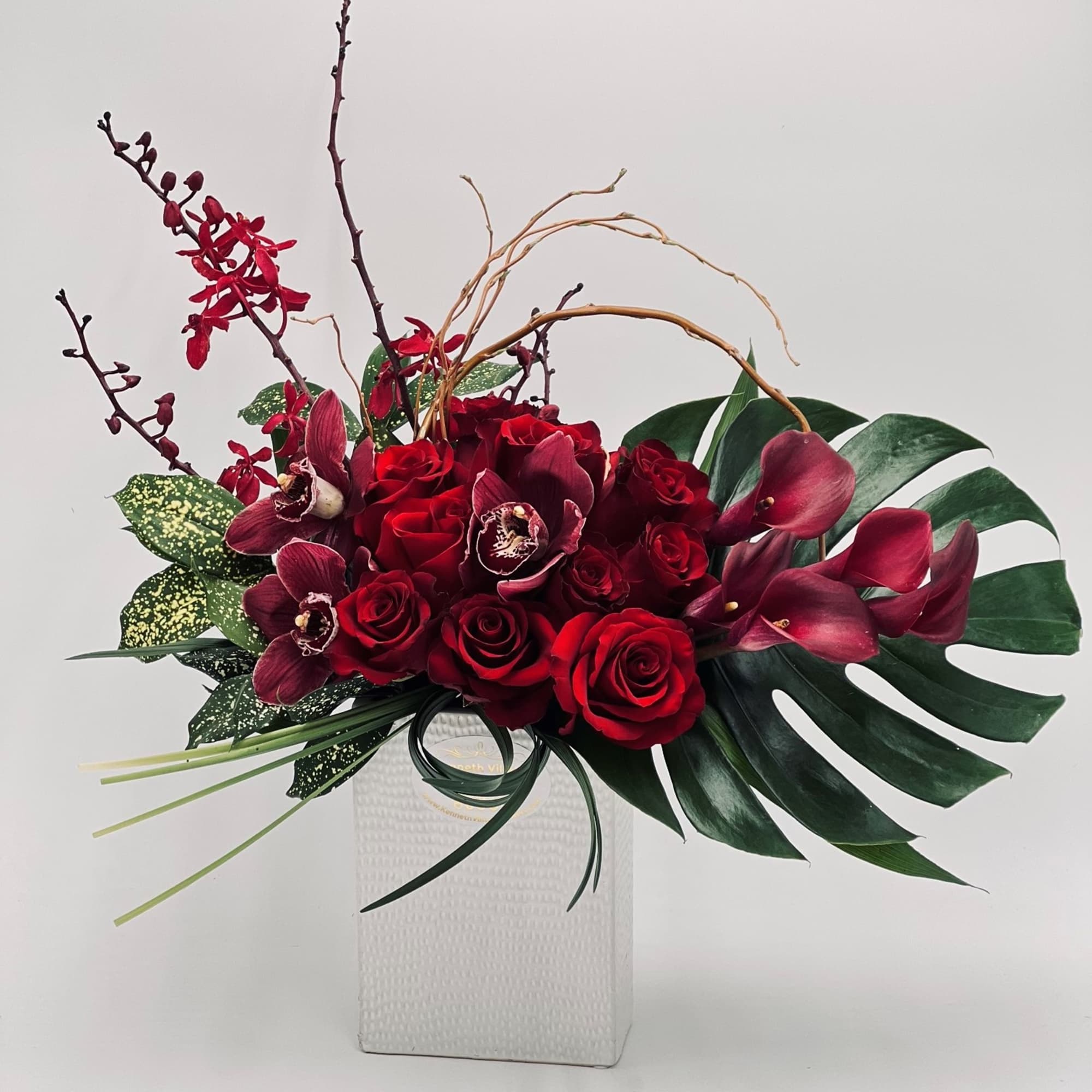 Red roses and burgundy orchids in a white vase