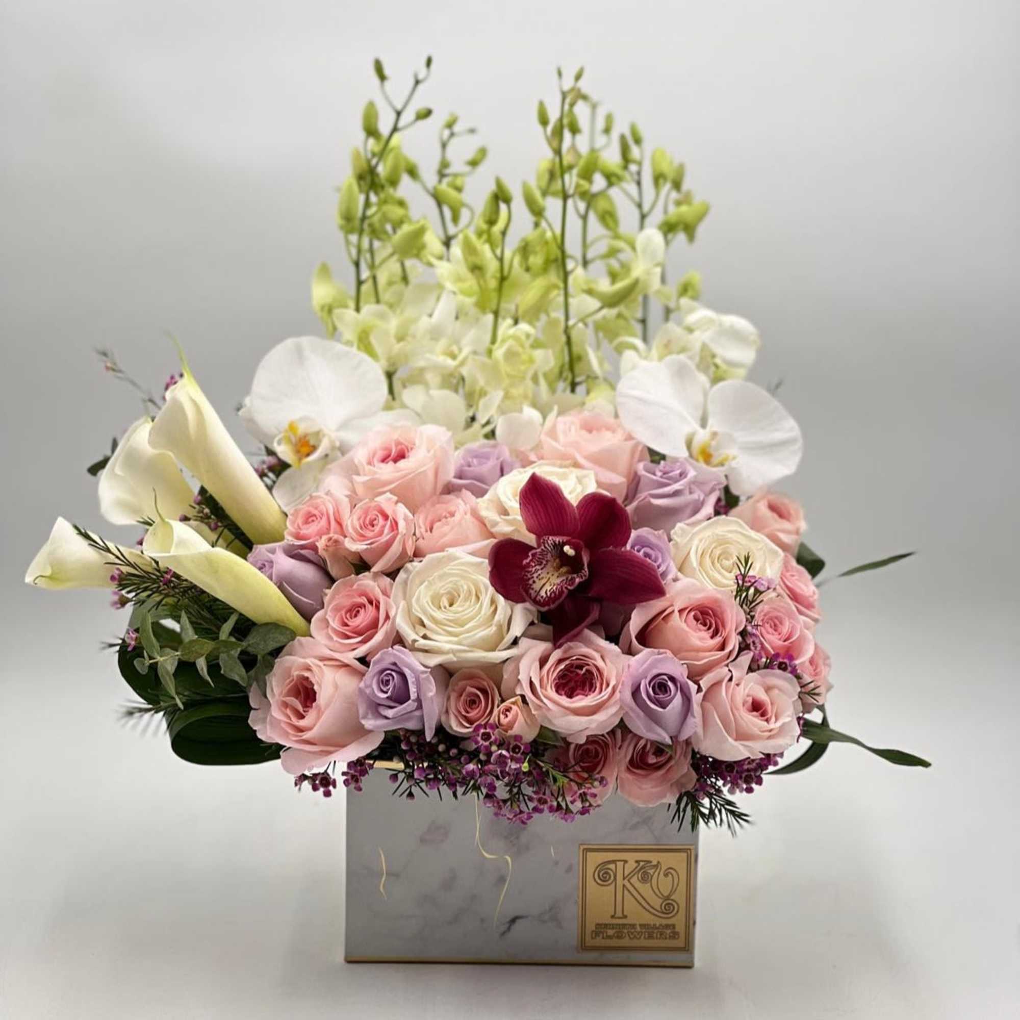Pink and lavender roses with white orchids in a square box