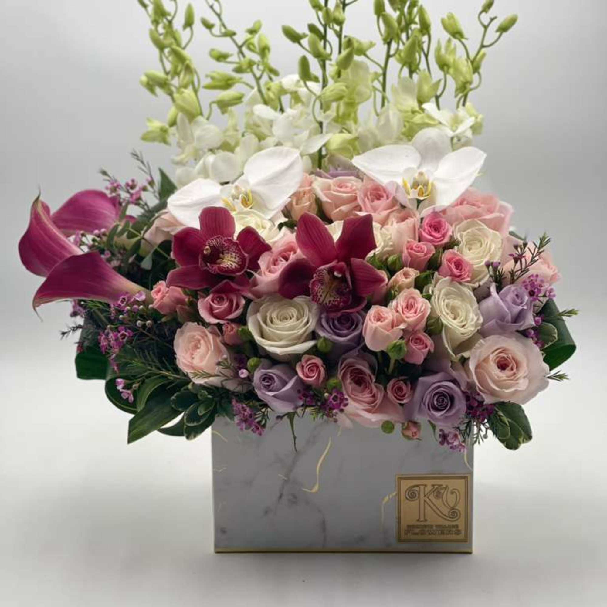 Mixed bouquet of pink, white, and purple flowers in a square box