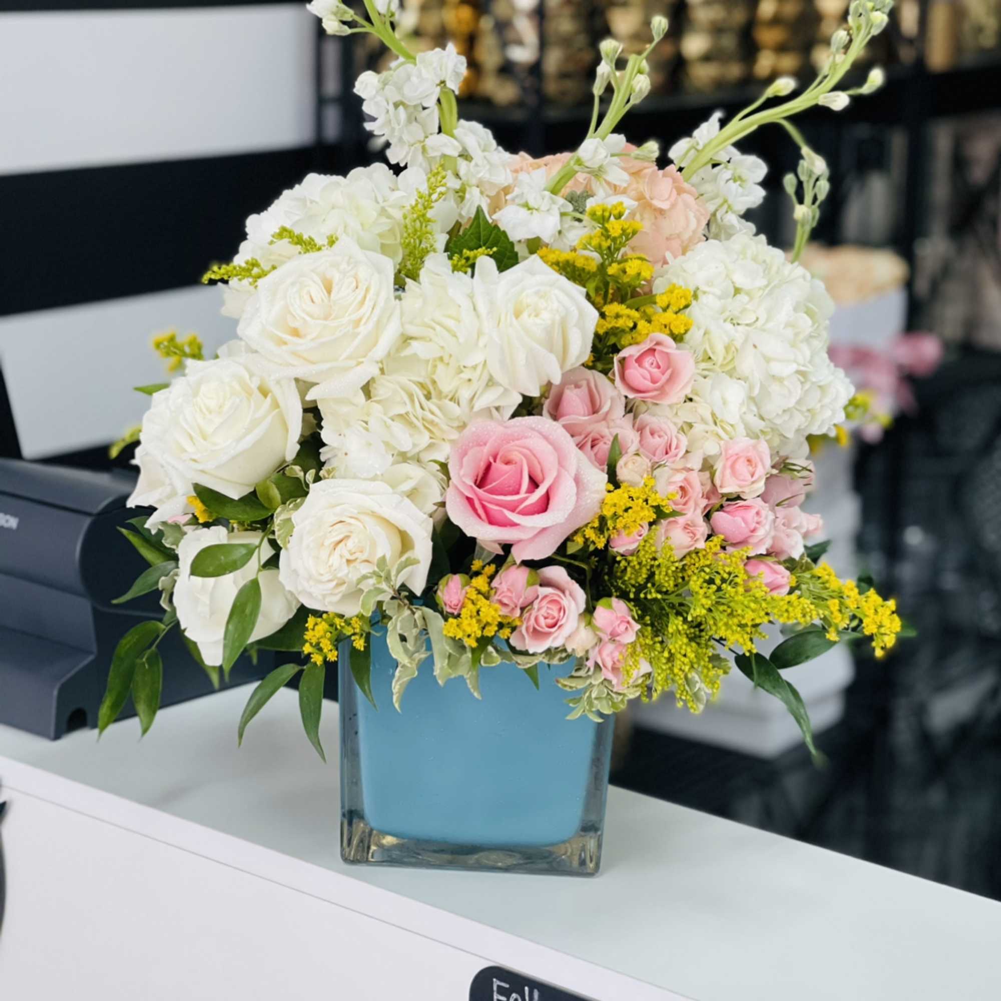 Pink and white rose bouquet in a blue glass vase