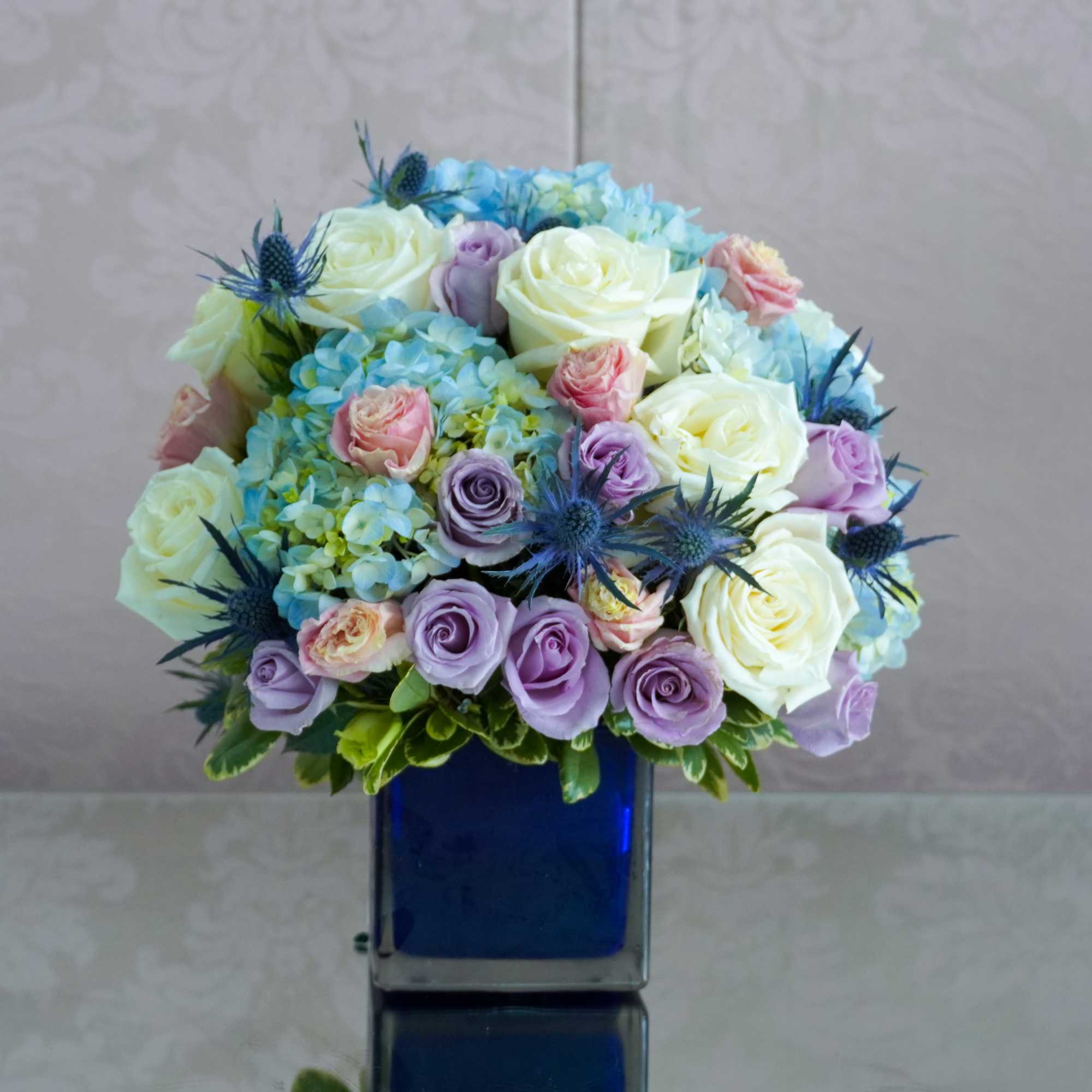 Bouquet of pastel roses and blue hydrangeas in a blue vase