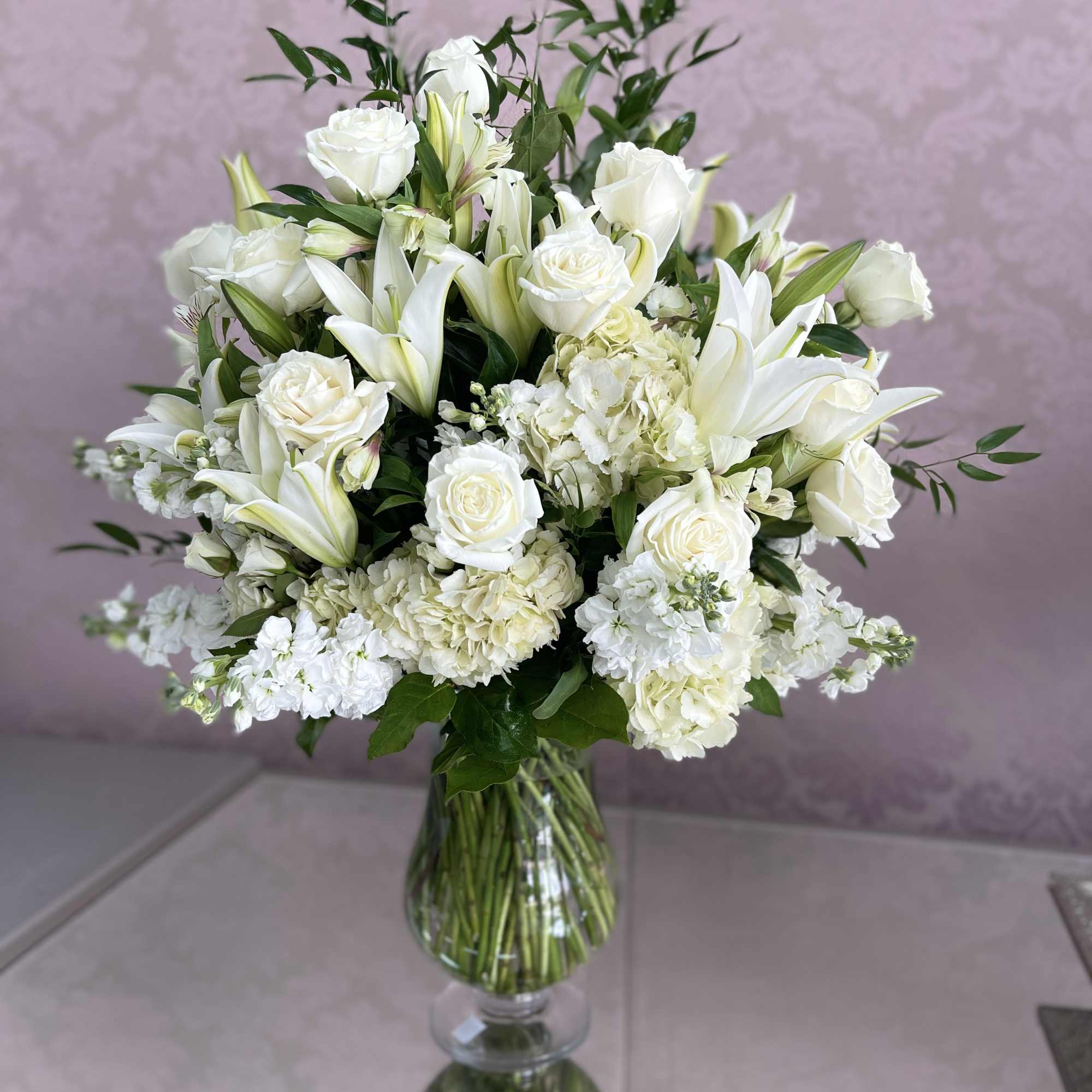 White roses and lilies arranged in a clear glass vase