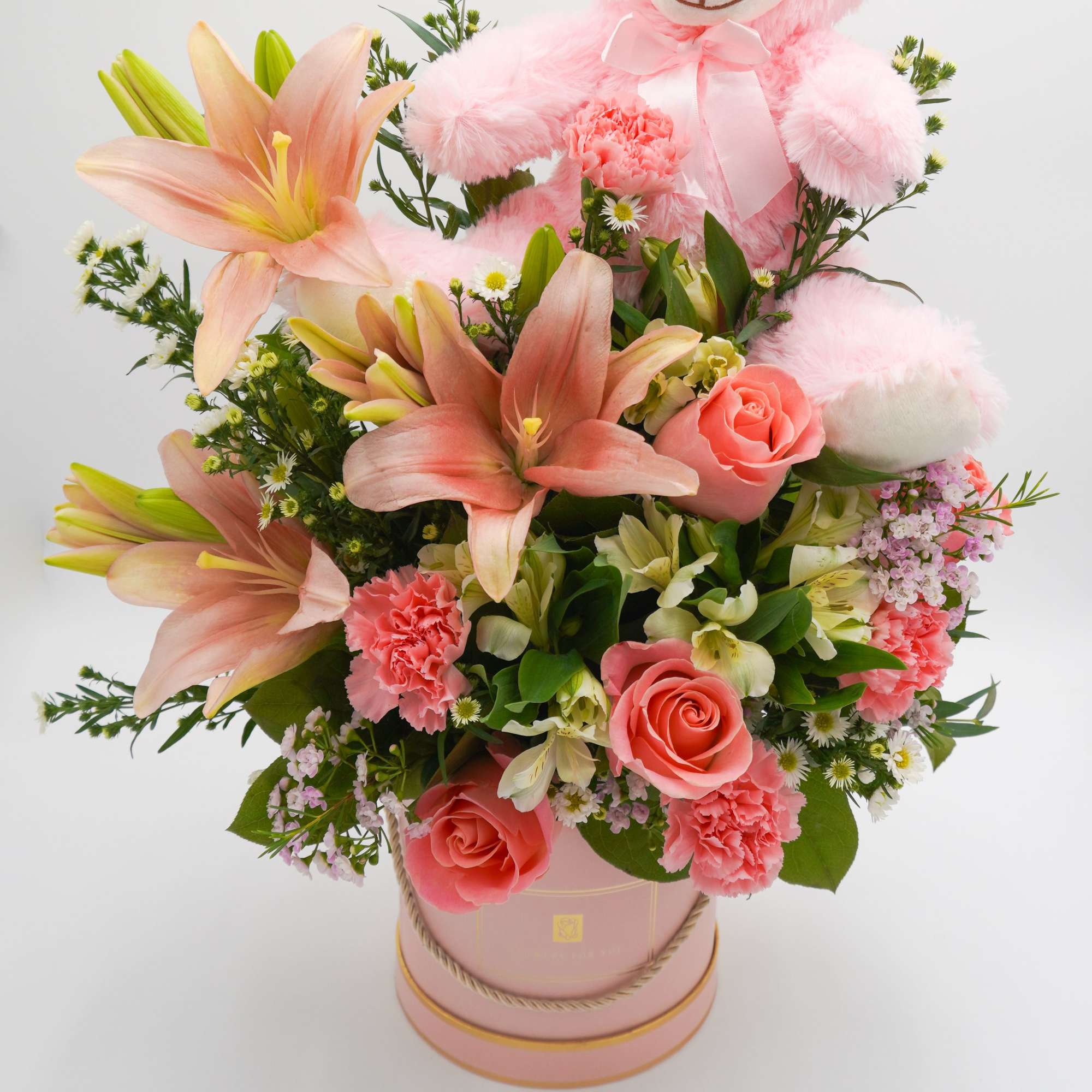 Pink lilies and roses arranged in a round pink hatbox