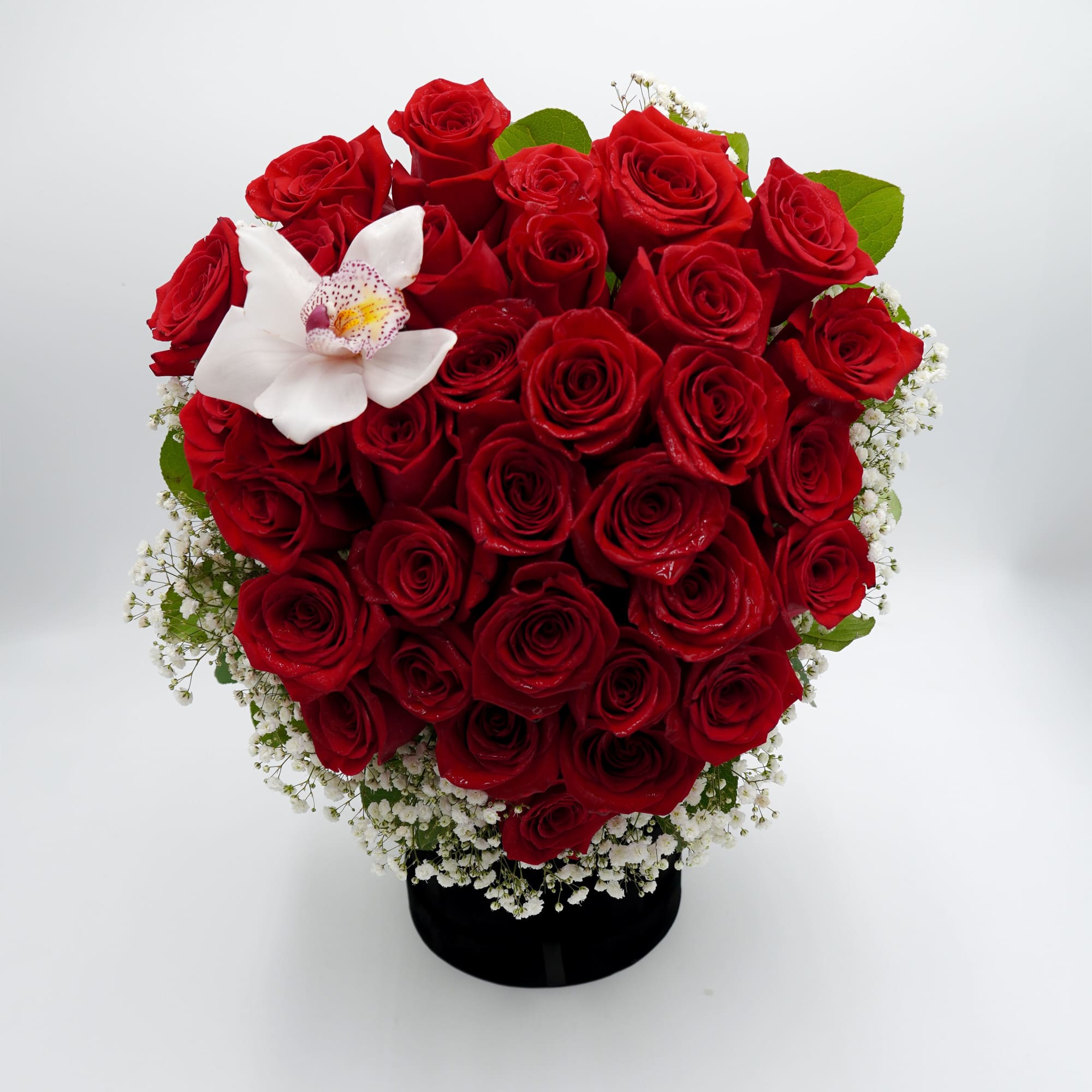 Red rose bouquet with a white orchid in a black vase