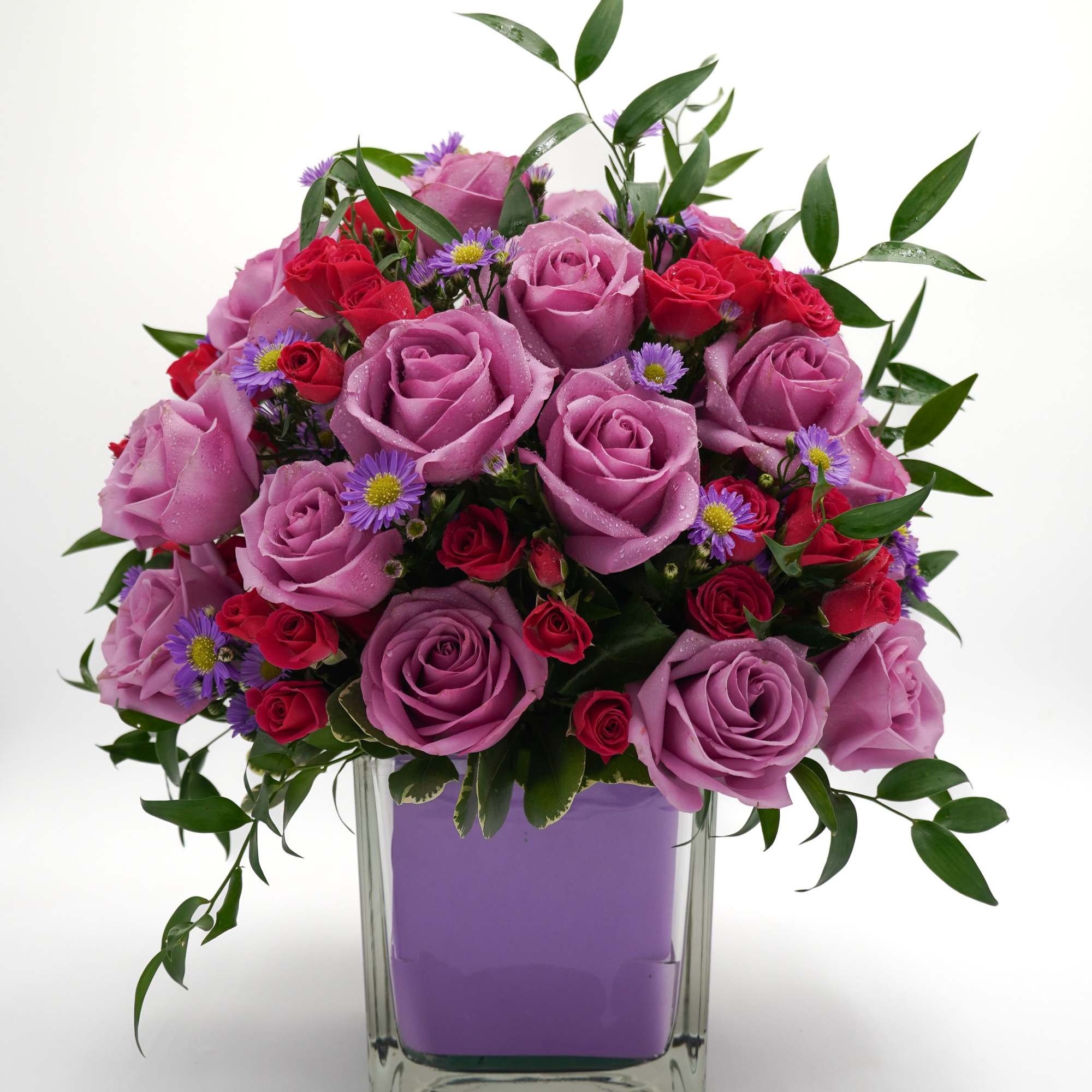 Lavender and red rose bouquet in a clear square vase