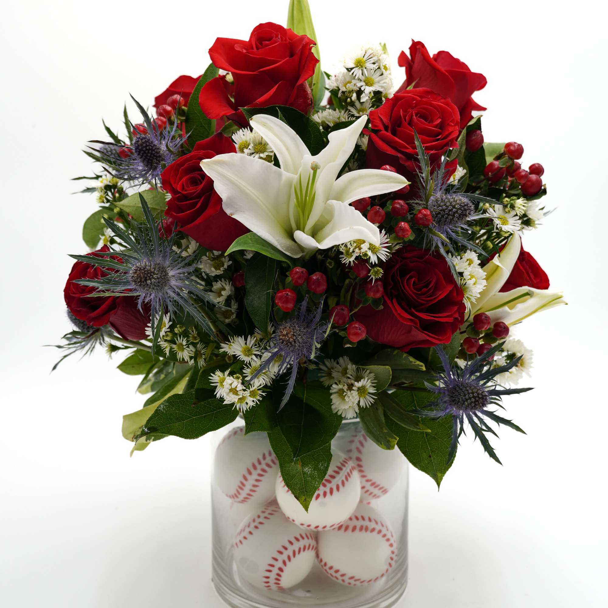 Red roses and a white lily in a glass vase filled with baseballs