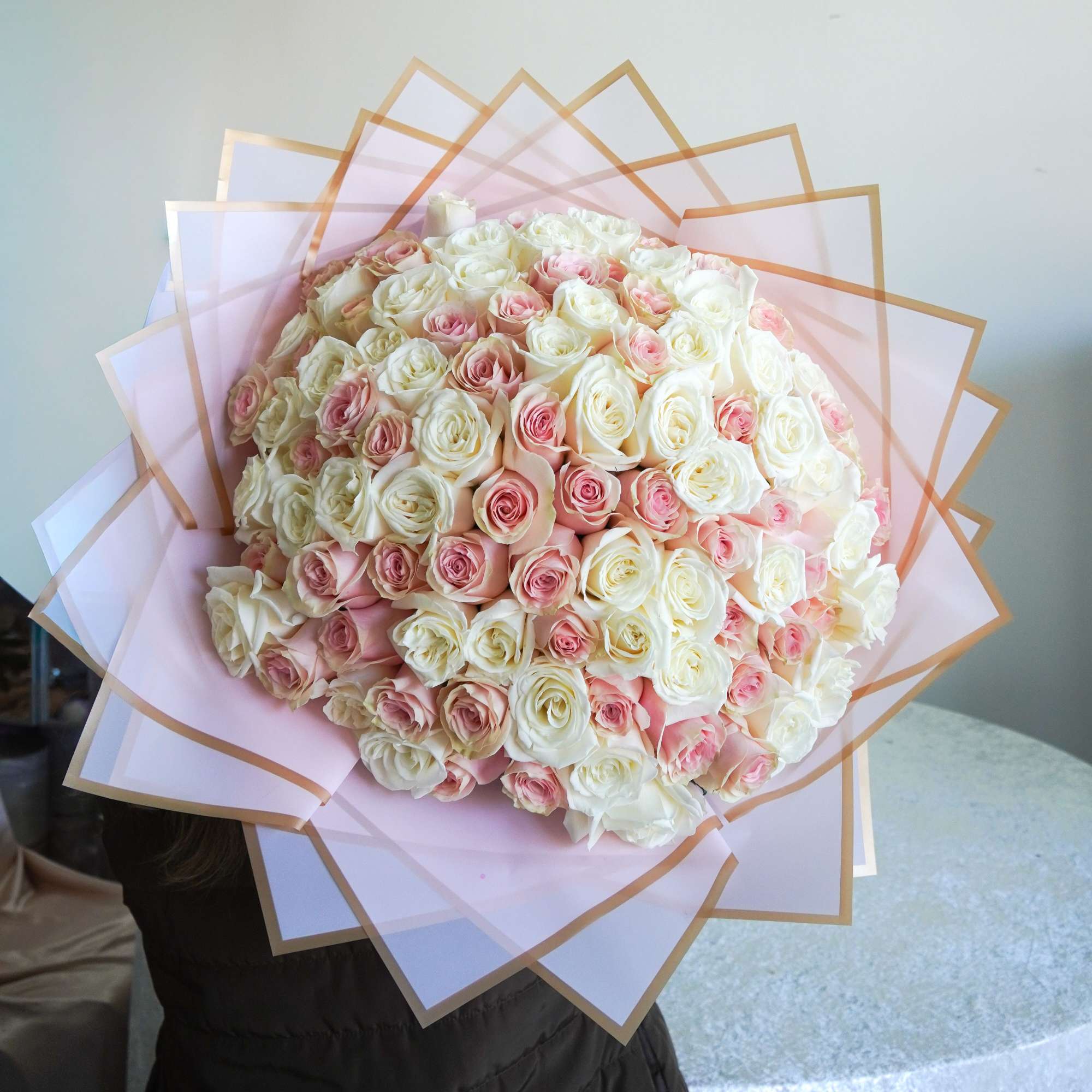 A luxurious bouquet of fresh blush pink and white roses, beautifully wrapped