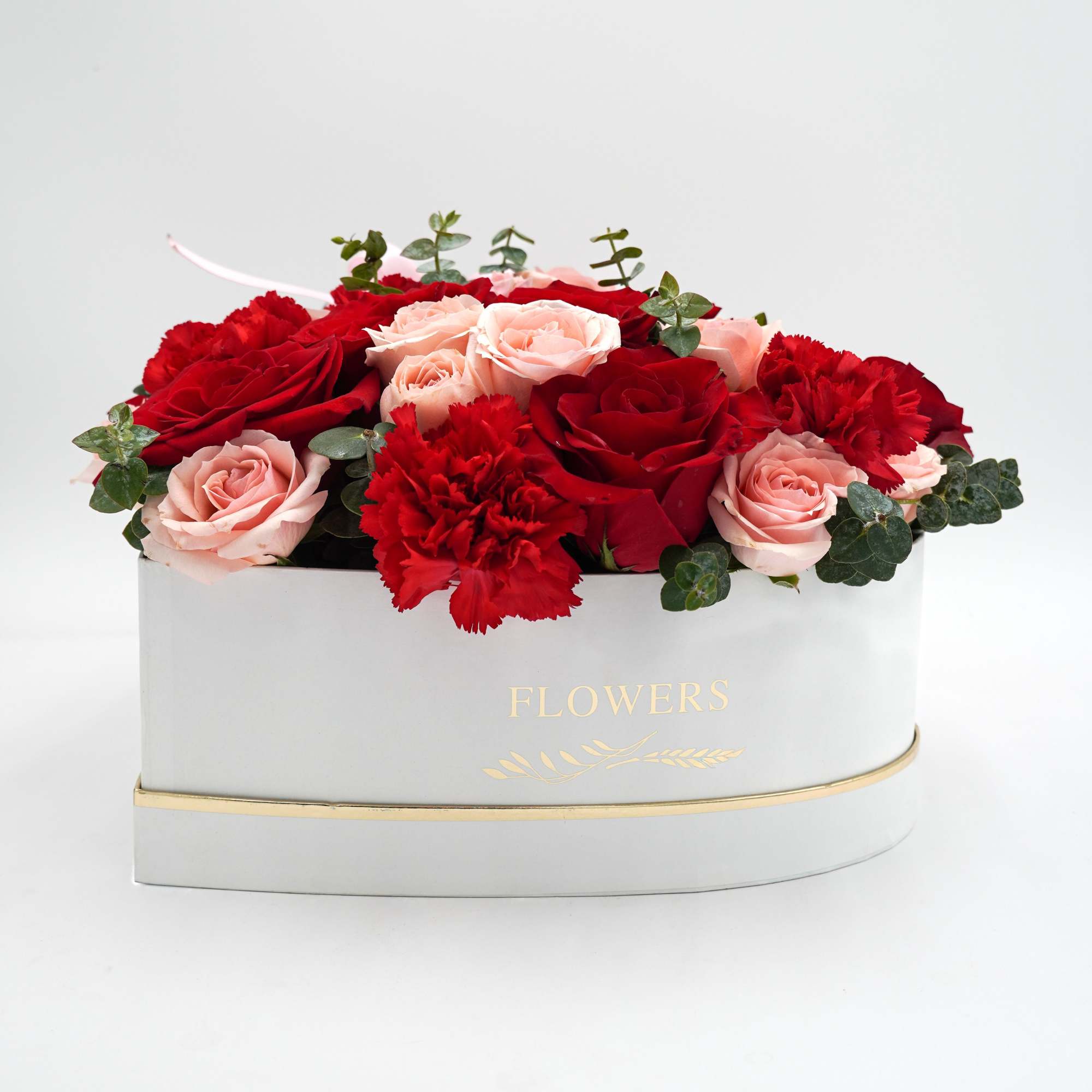 Red and blush roses with carnations in a white heart-shaped box