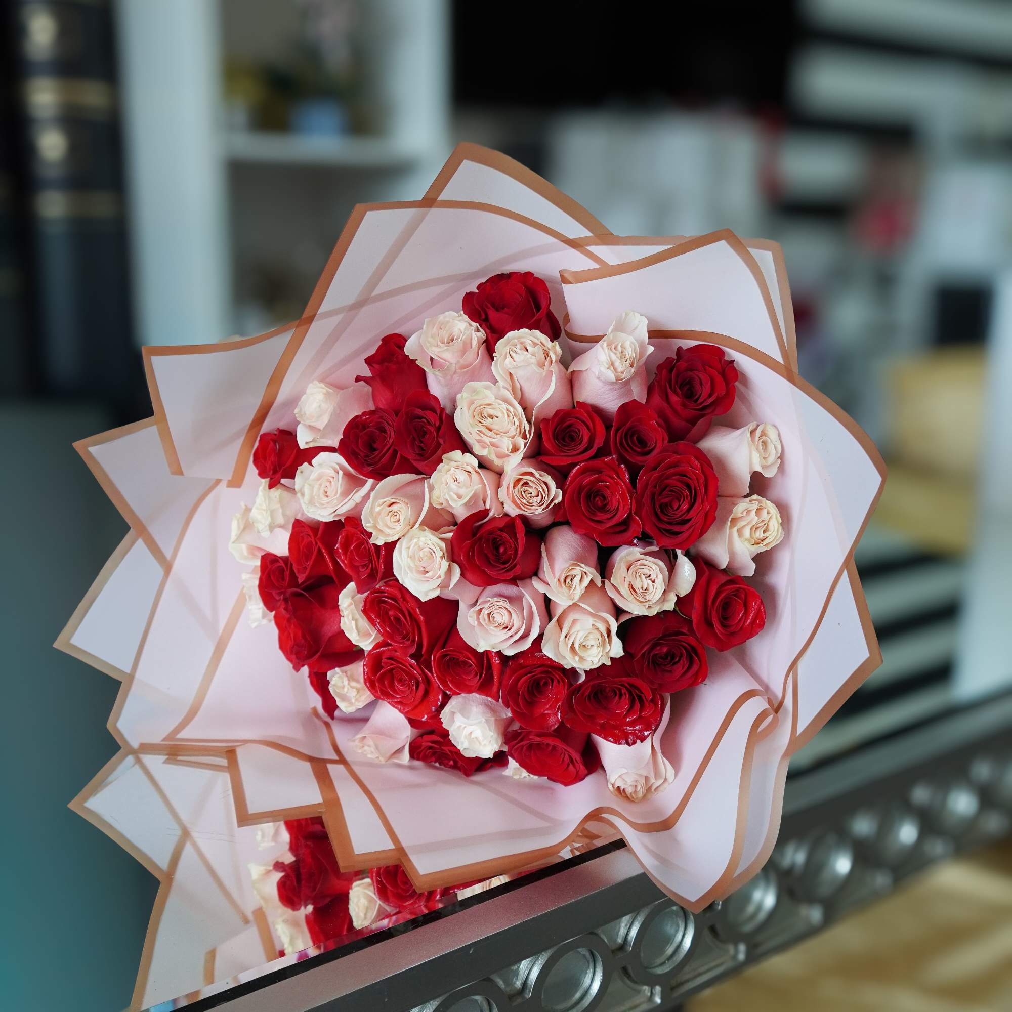 A romantic bouquet of vibrant red and pink roses, beautifully wrapped for