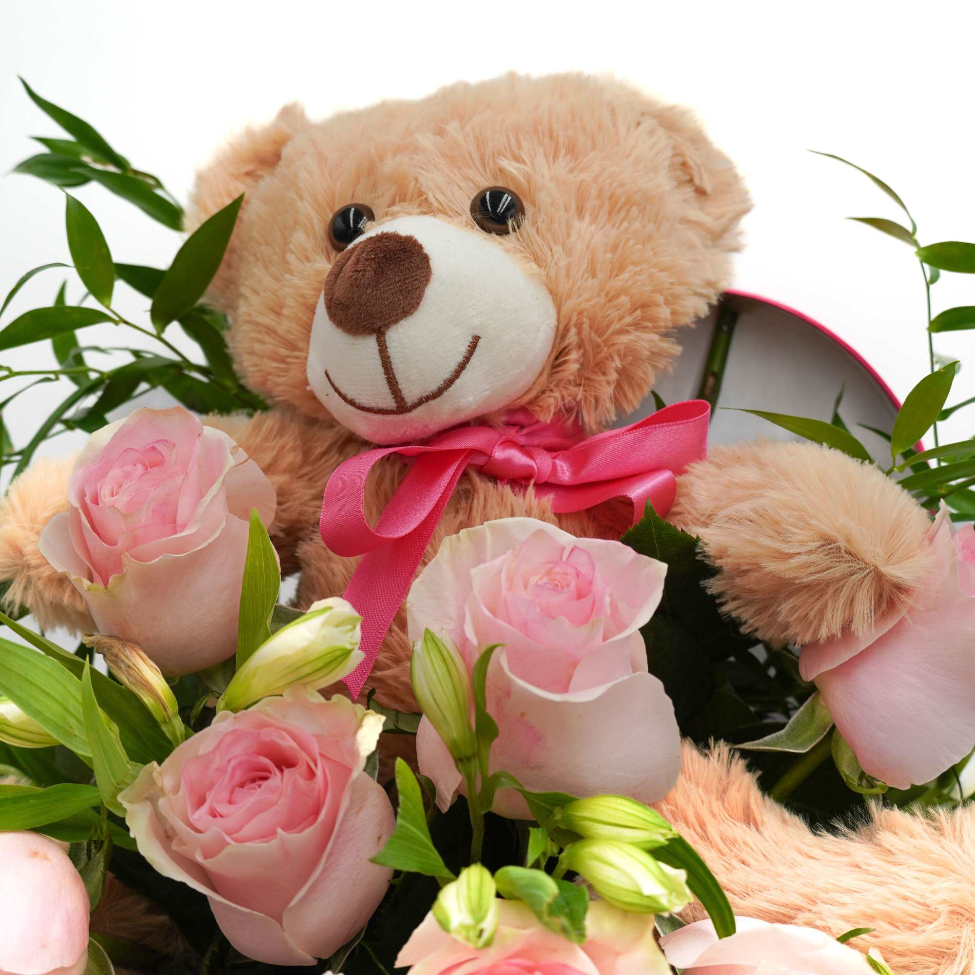 Teddy bear with pink roses and green foliage