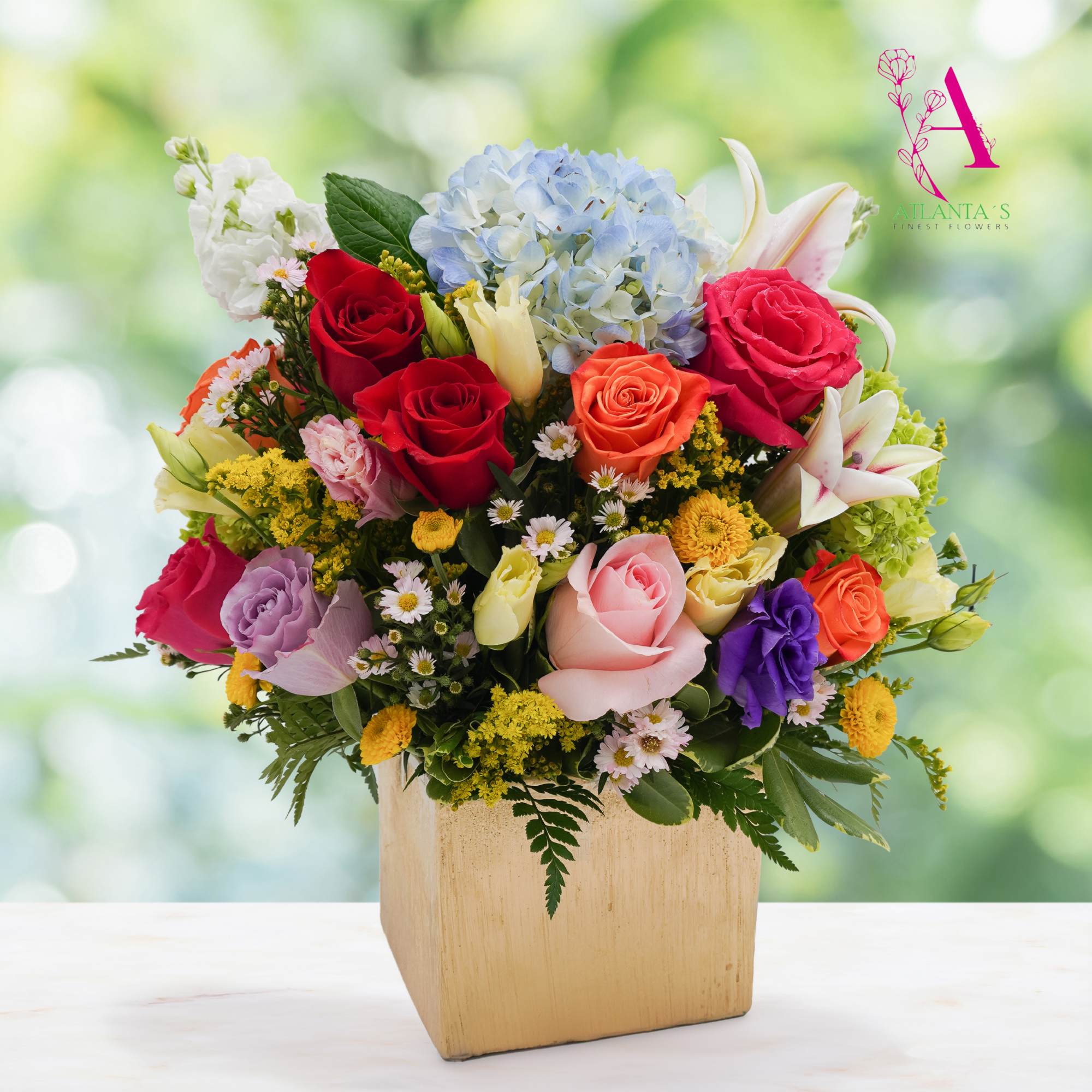 Mixed bouquet of roses, hydrangea, and lilies in a square wooden vase