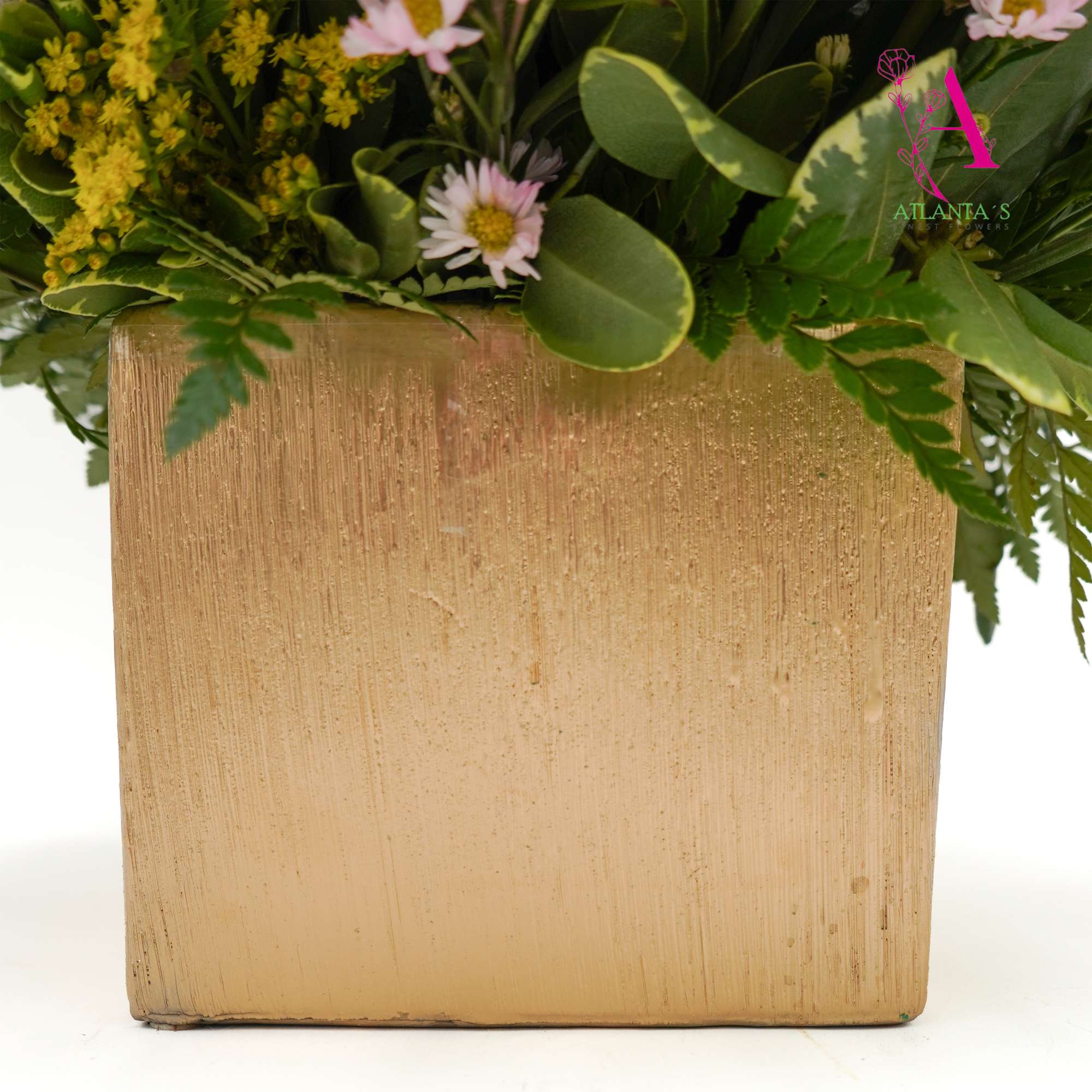 Floral arrangement in a gold square container with small pink and yellow blooms