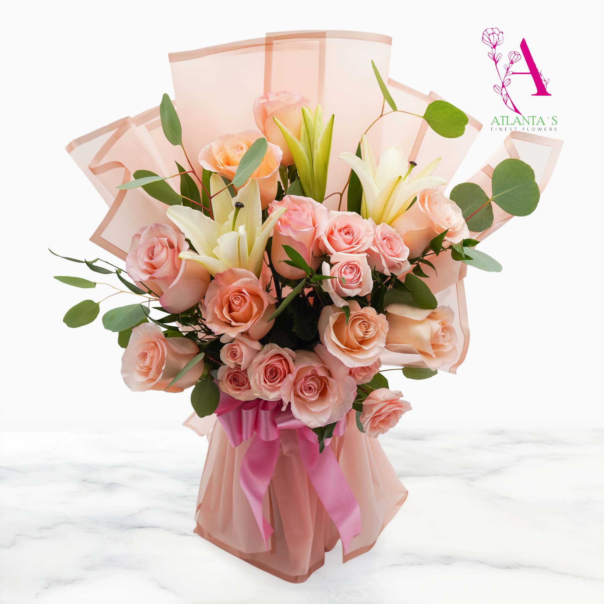 Peach roses and white lilies in pink wrapping with a ribbon