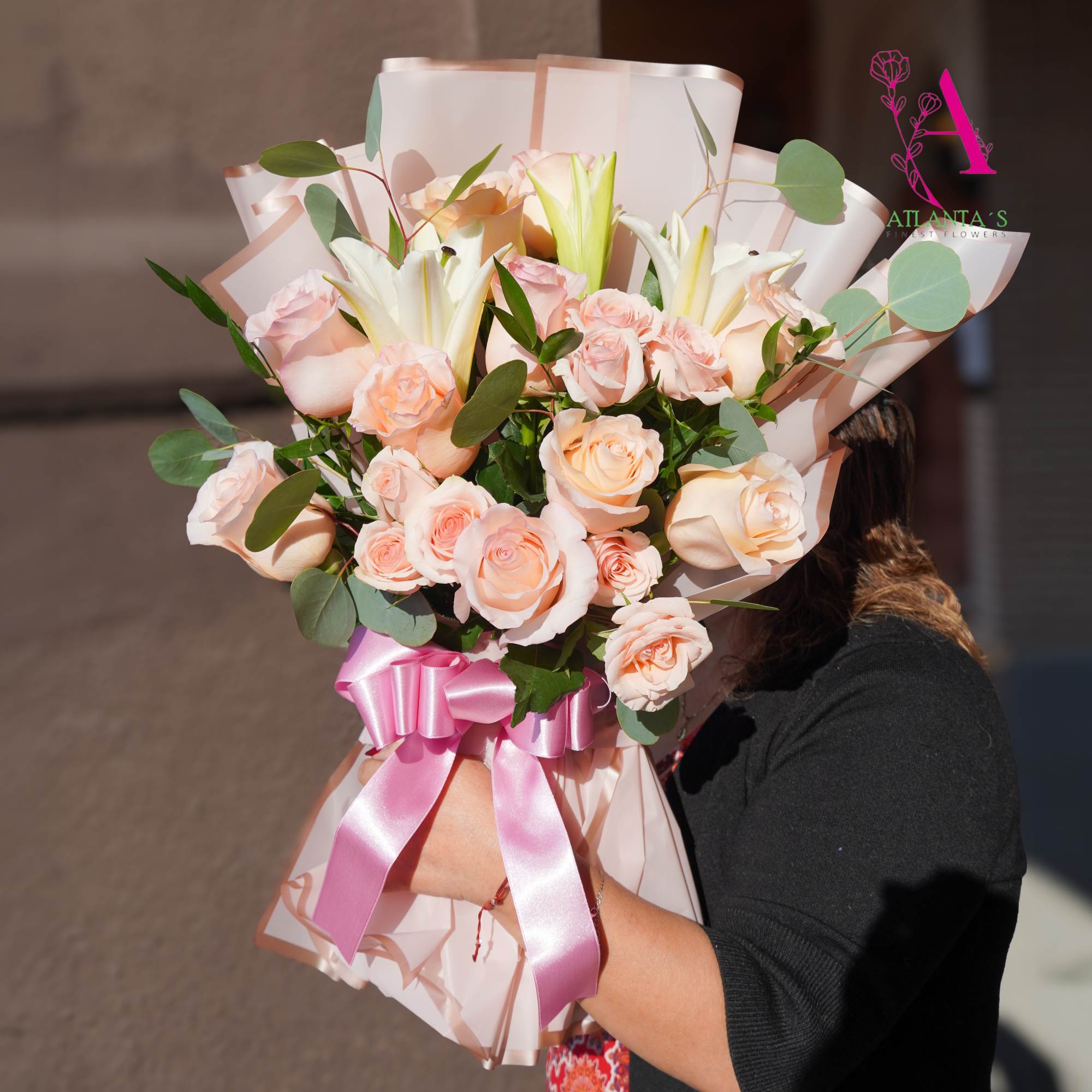 Bouquet of pale pink roses and white lilies wrapped with a pink ribbon