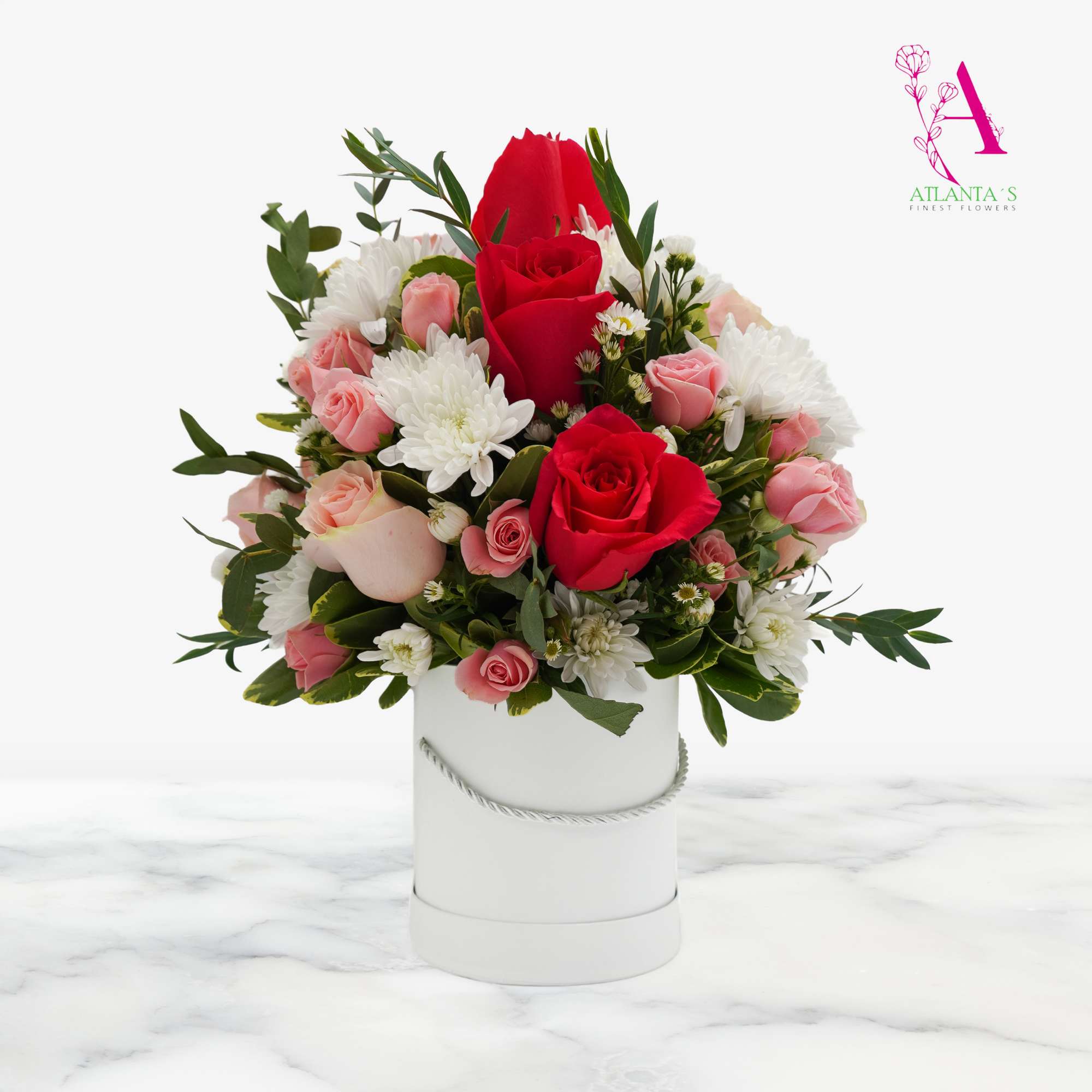 Bouquet of red and pink roses with white blooms in a white hatbox