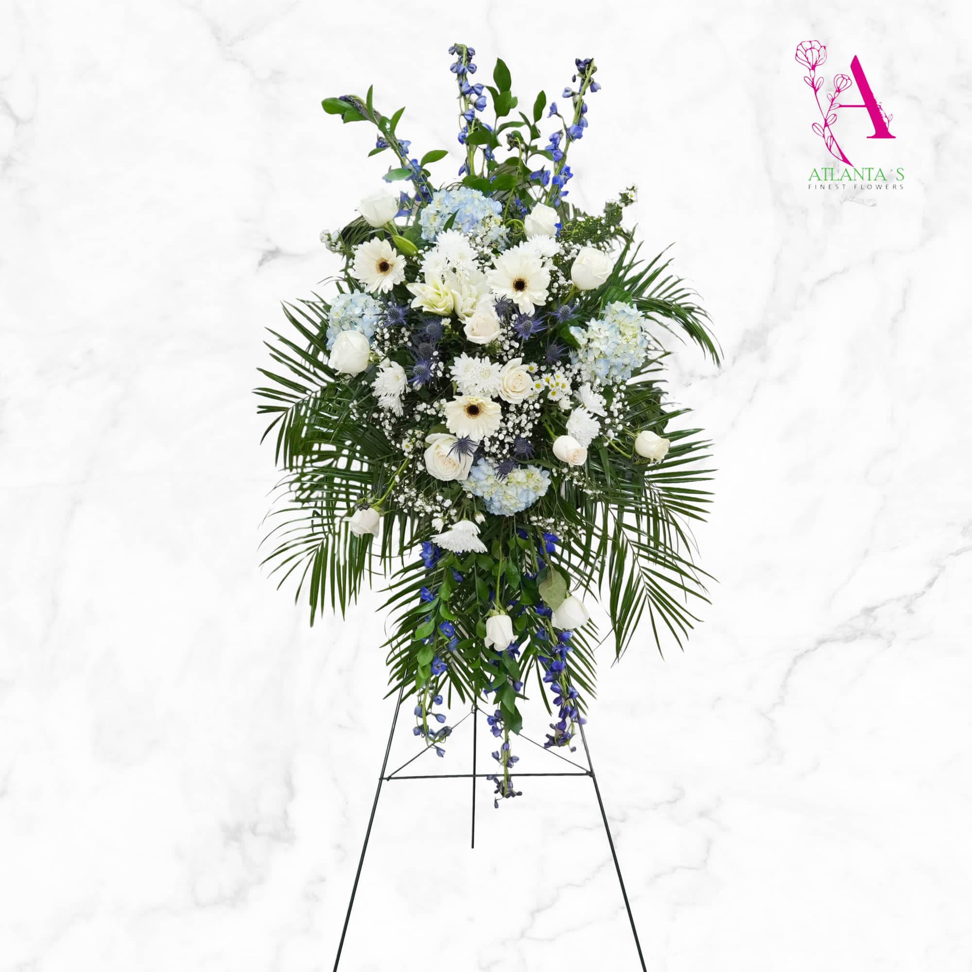Standing floral spray with white and blue flowers on a metal easel