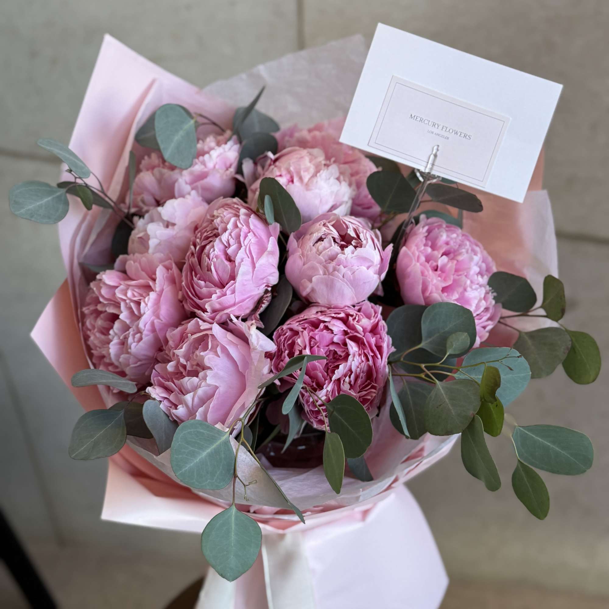 Pink peony bouquet with eucalyptus in pastel wrapping