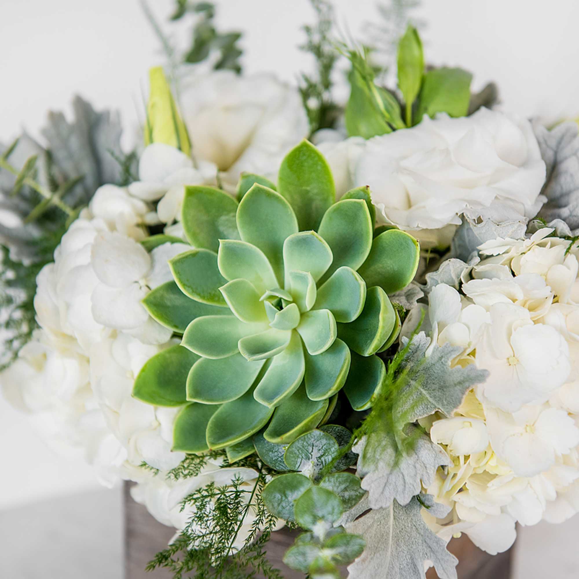 White floral arrangement with a green succulent centerpiece