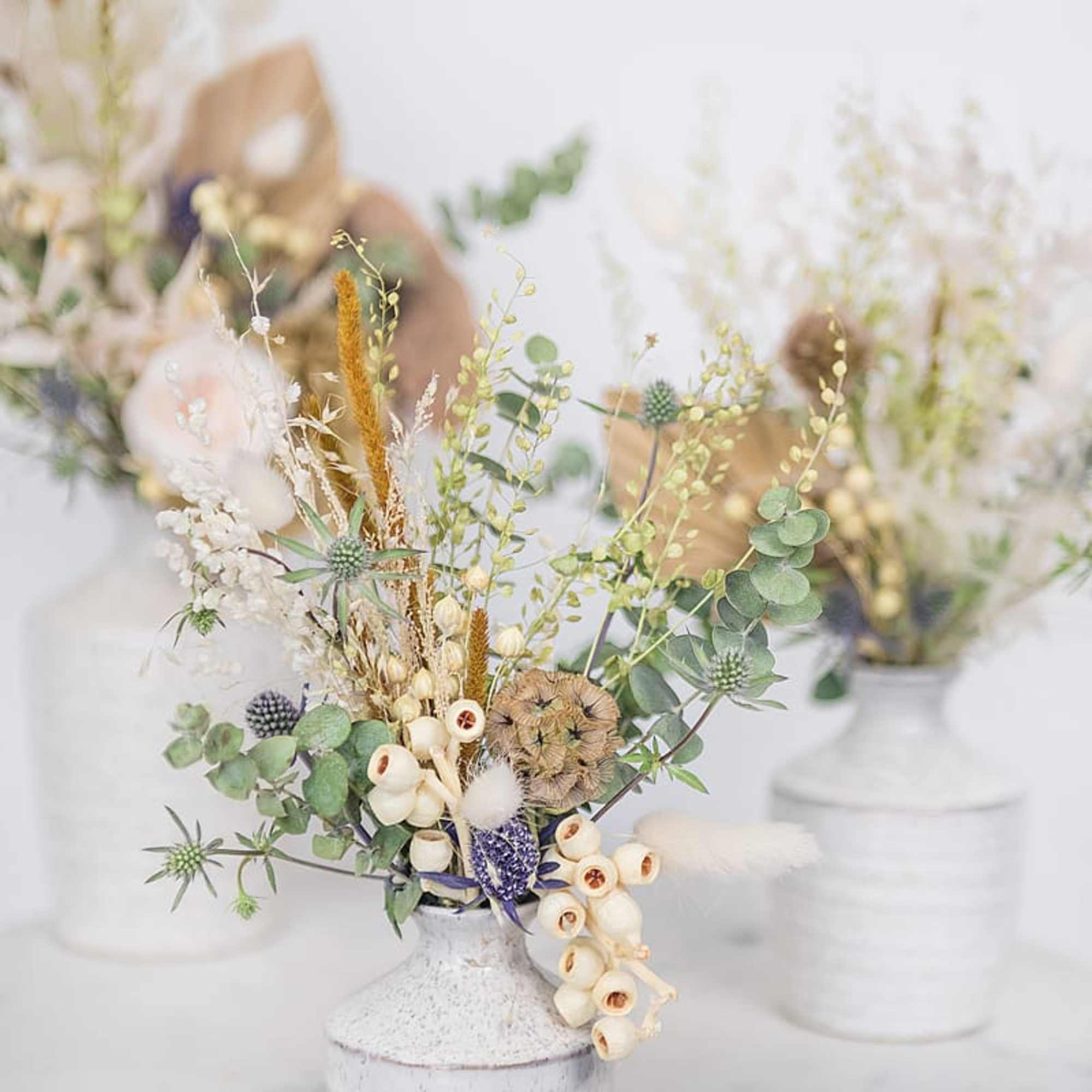 Dried floral arrangement in a white vase with eucalyptus and cream accents
