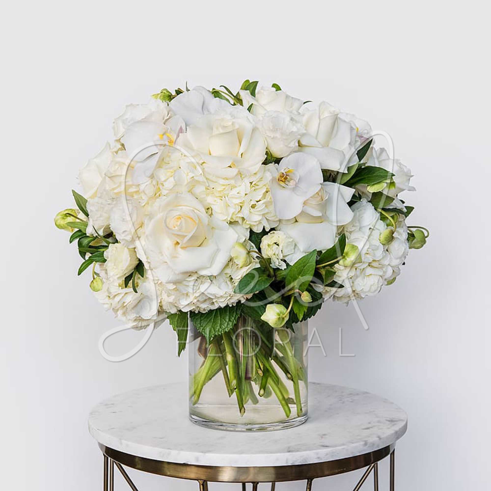 White roses and orchids arranged in a clear glass vase