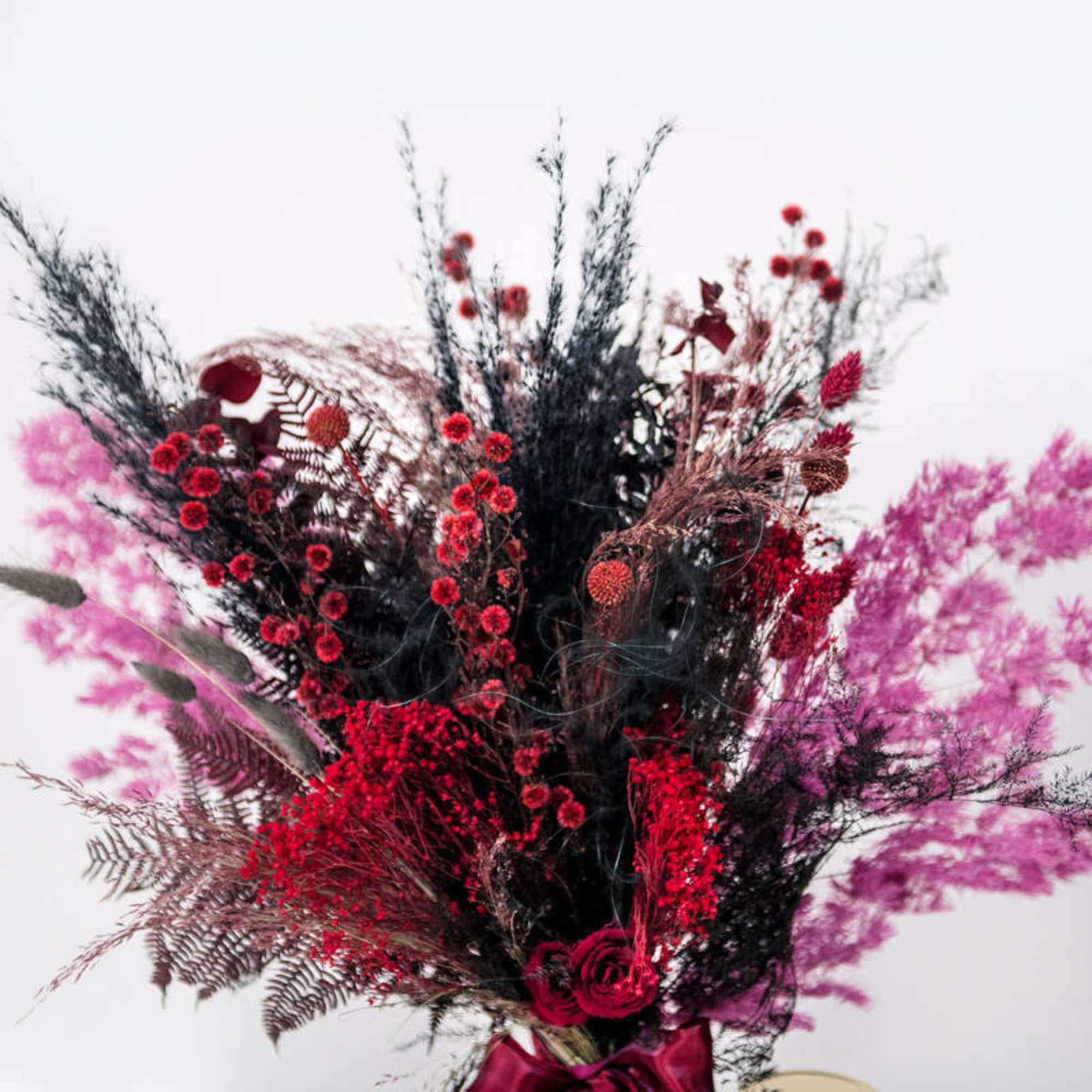 Tall bouquet of red and pink flowers with dark dried foliage