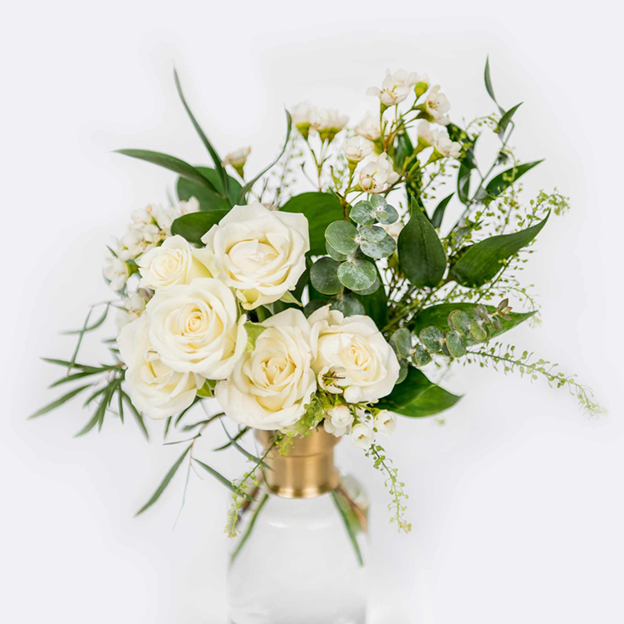 White roses in a clear vase with green foliage