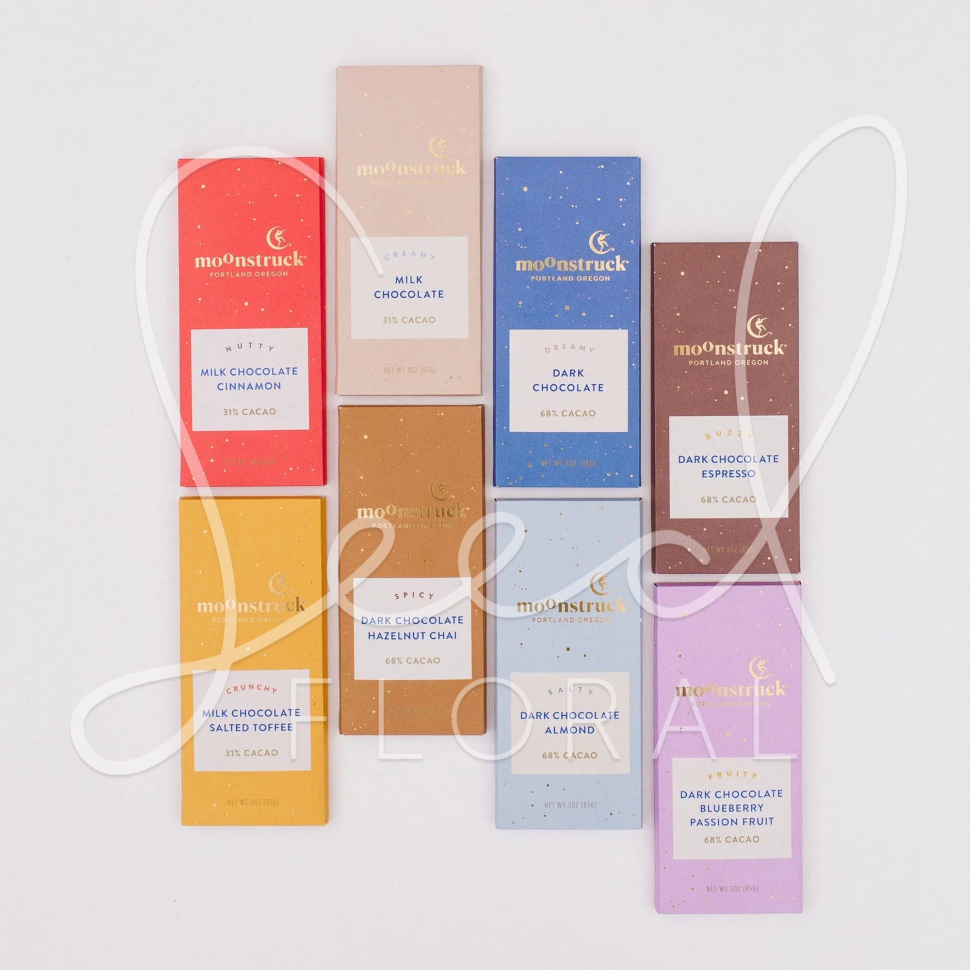 Nine assorted Moonstruck chocolate bars in colorful rectangular wrappers on a white background.