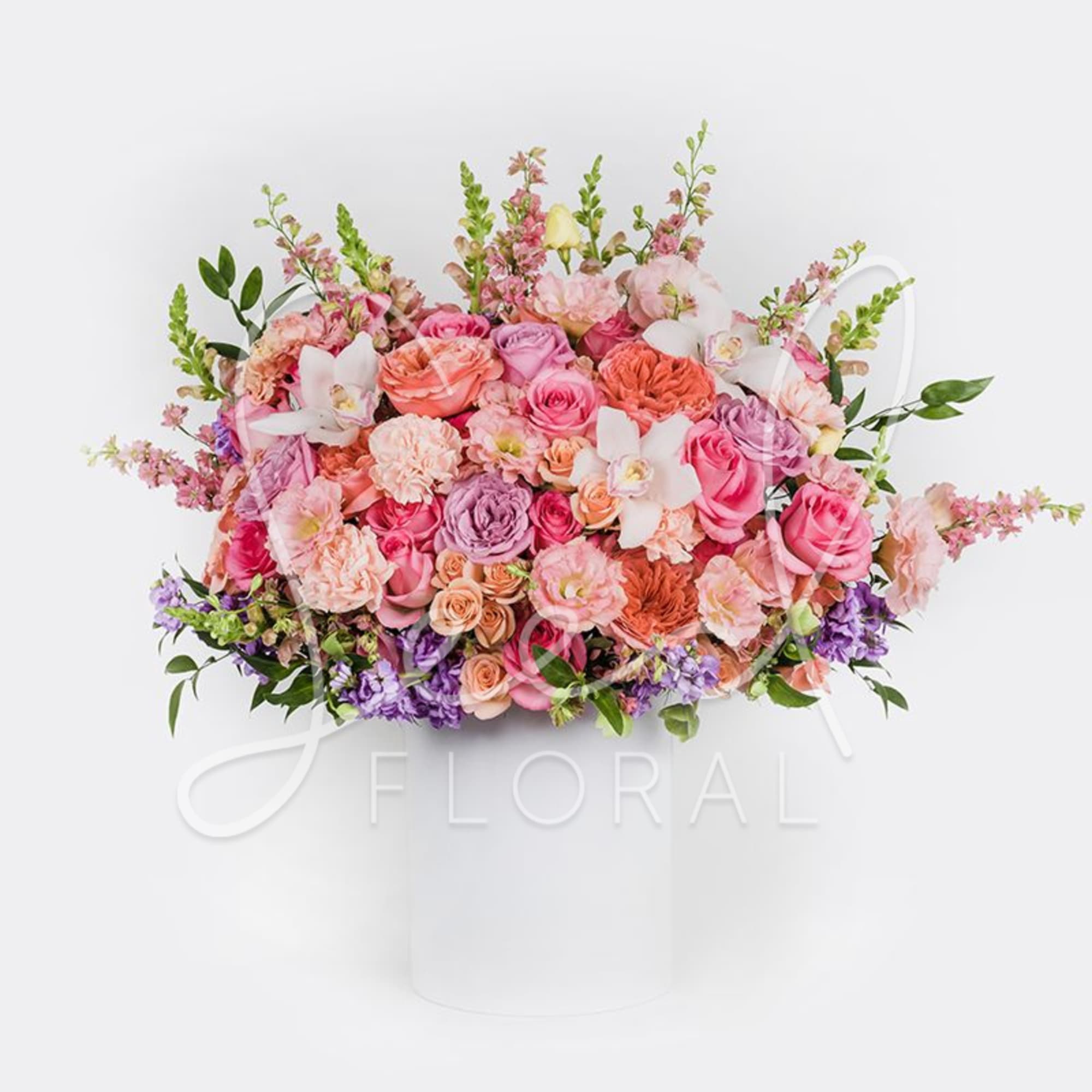 Pink and purple mixed flower arrangement in a white hatbox