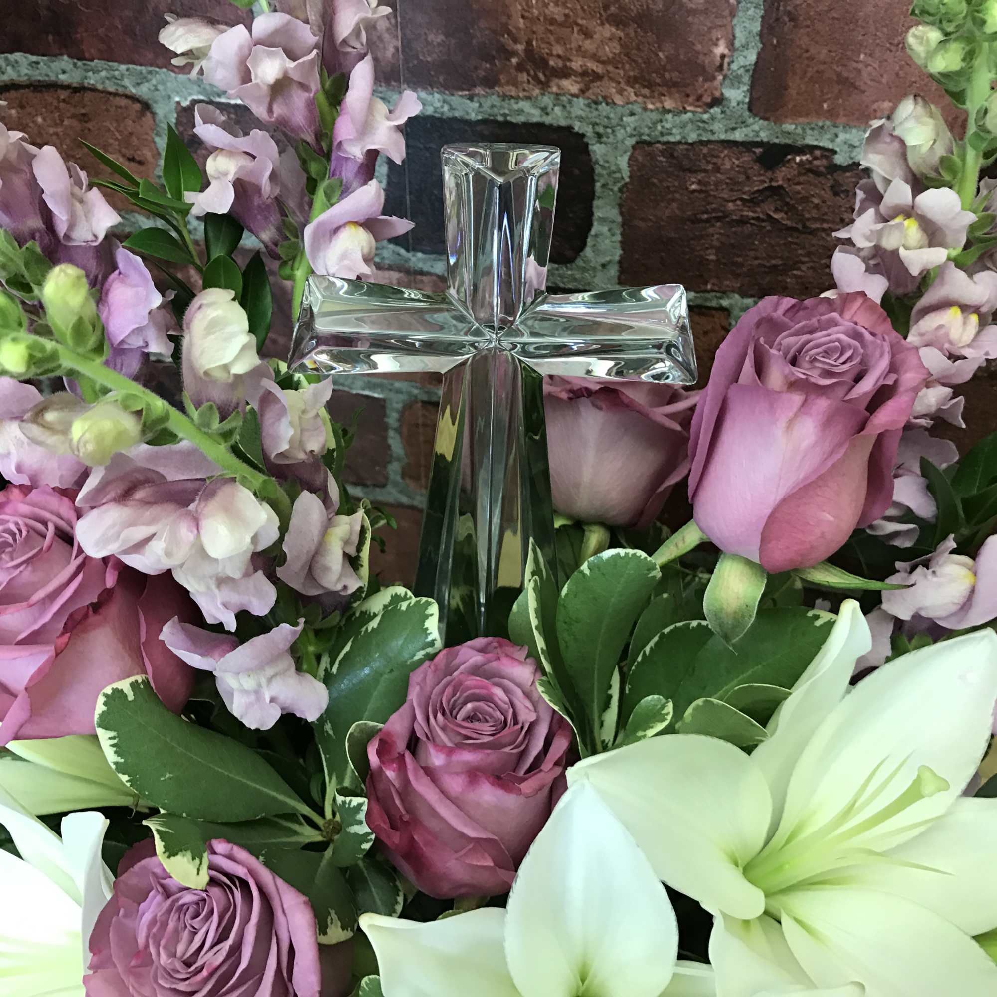 Pink roses and white lilies arranged around a clear glass cross, photo 2 of 2