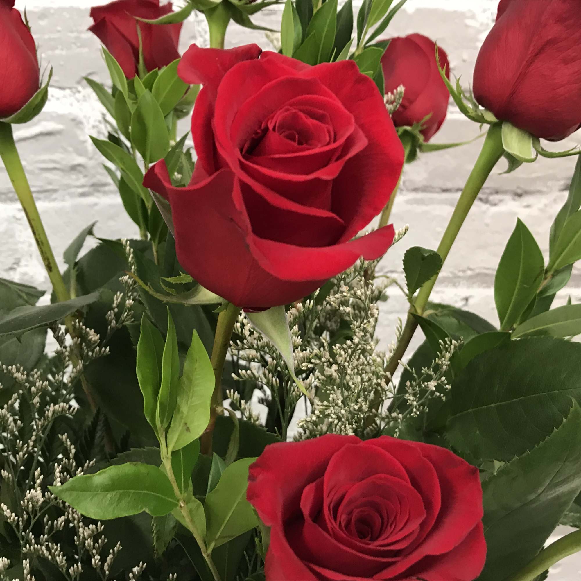Close-up bouquet of red roses with greenery and filler flowers