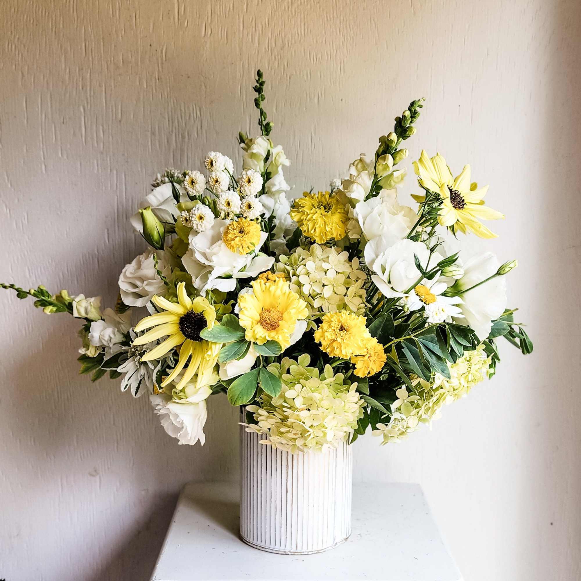 Yellow and white floral arrangement in a ribbed white vase
