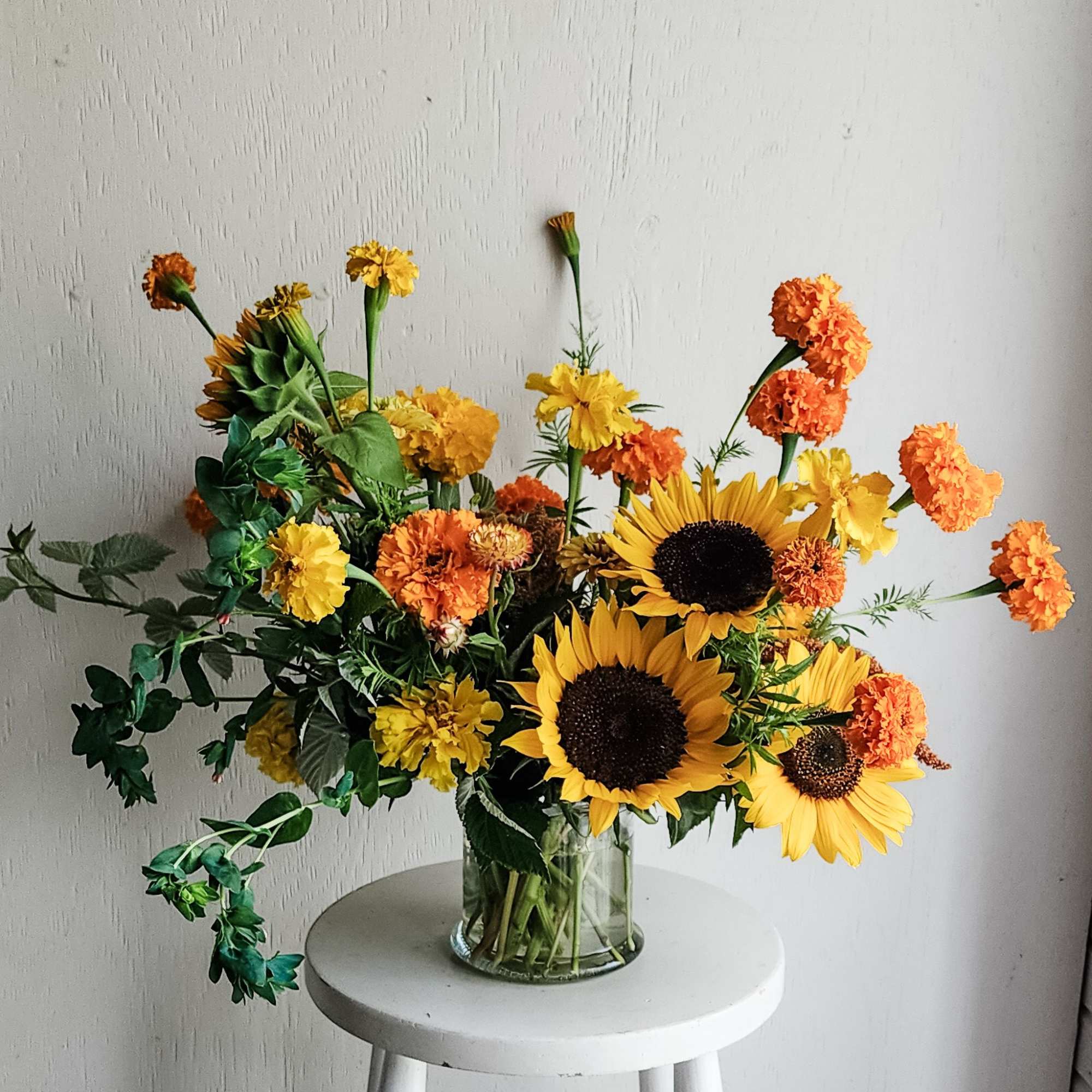 Sunflowers and orange marigolds in a clear glass vase