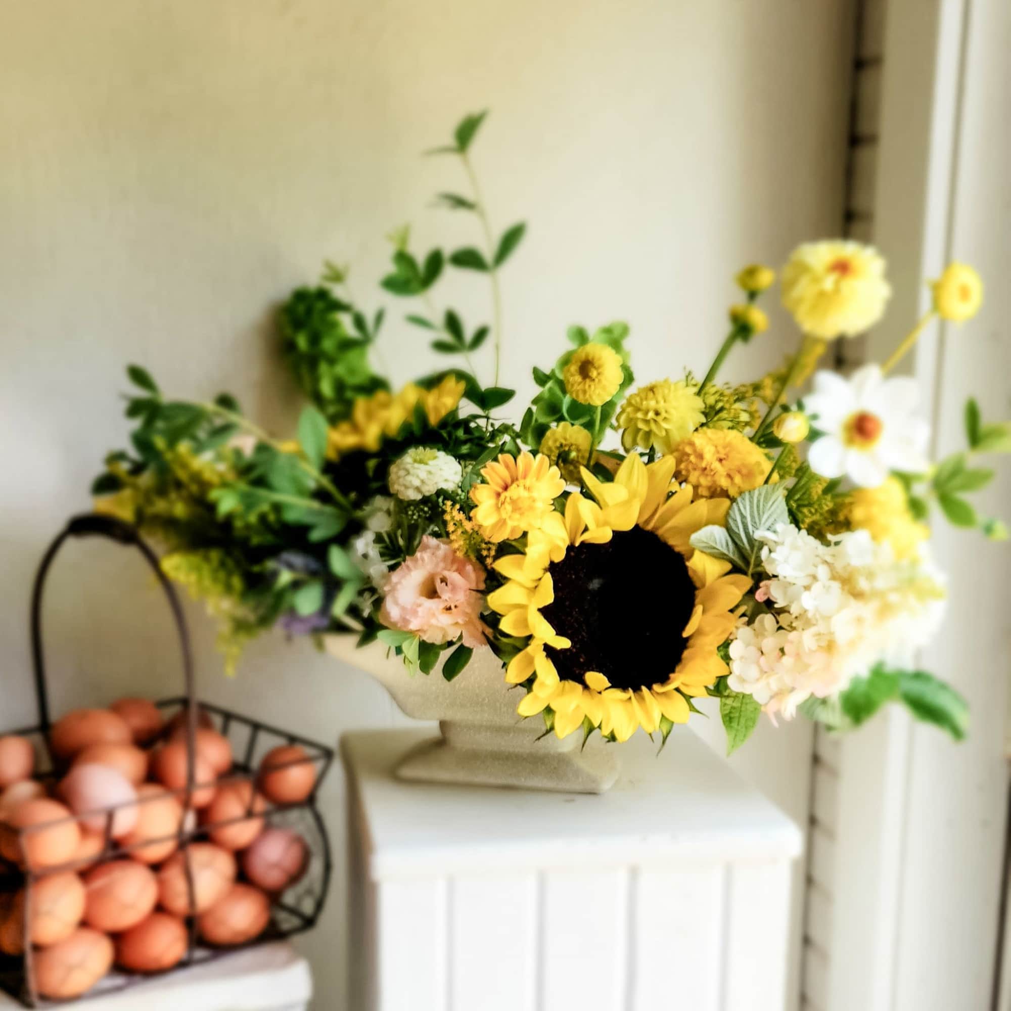Sunflower and mixed yellow flower arrangement in a pedestal vase