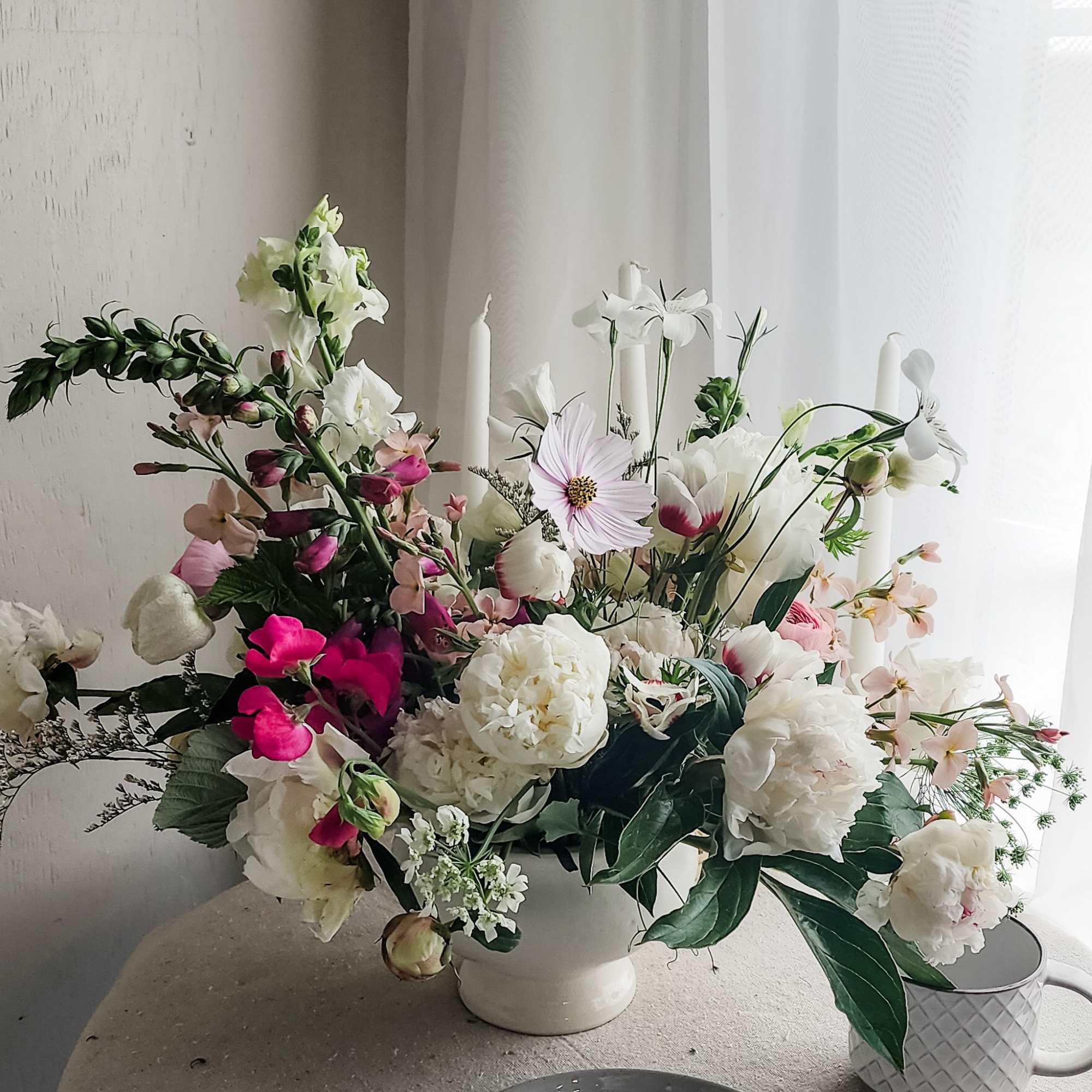 Large mixed floral arrangement in a white vase with pink and white blooms