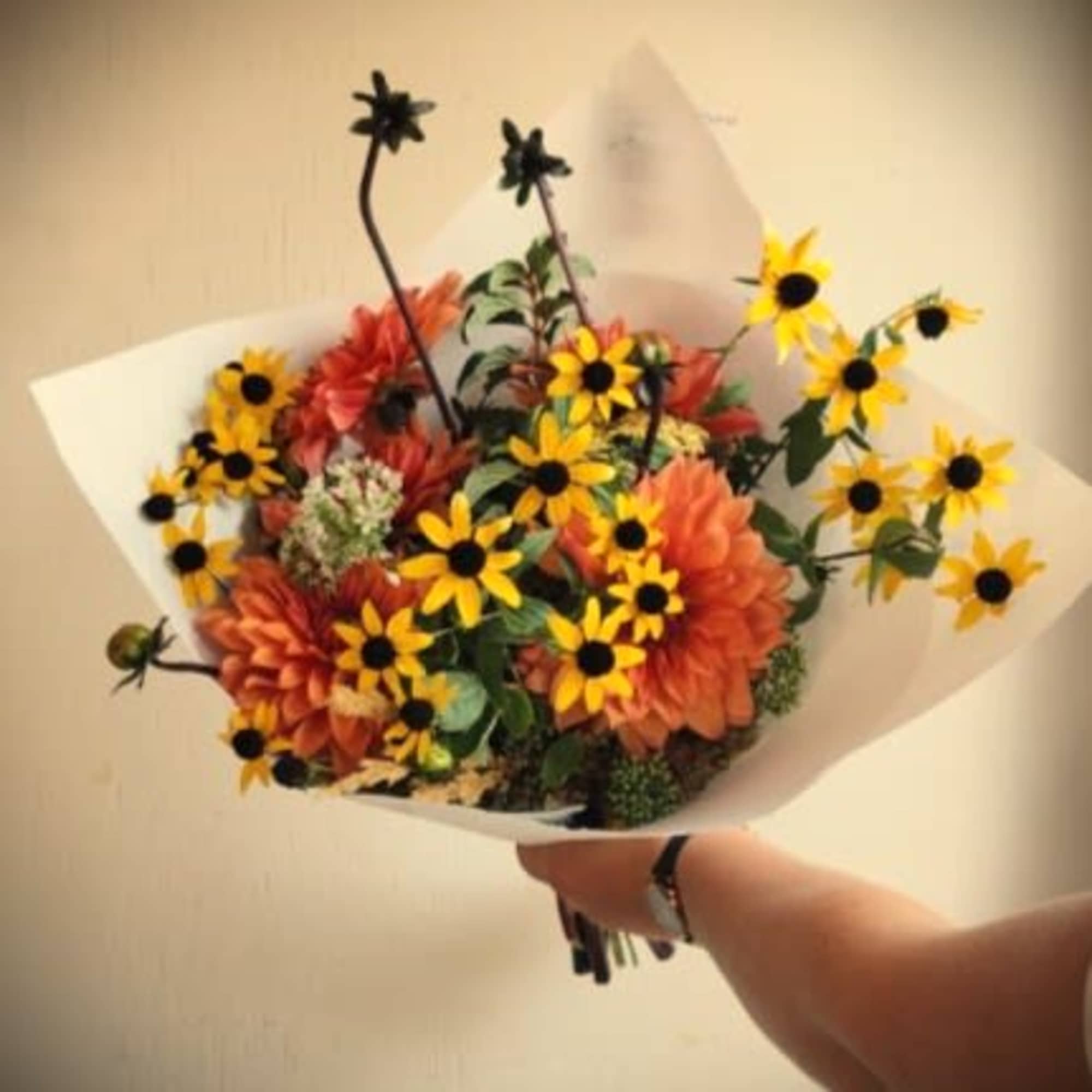 Bouquet of orange and yellow flowers wrapped in white paper